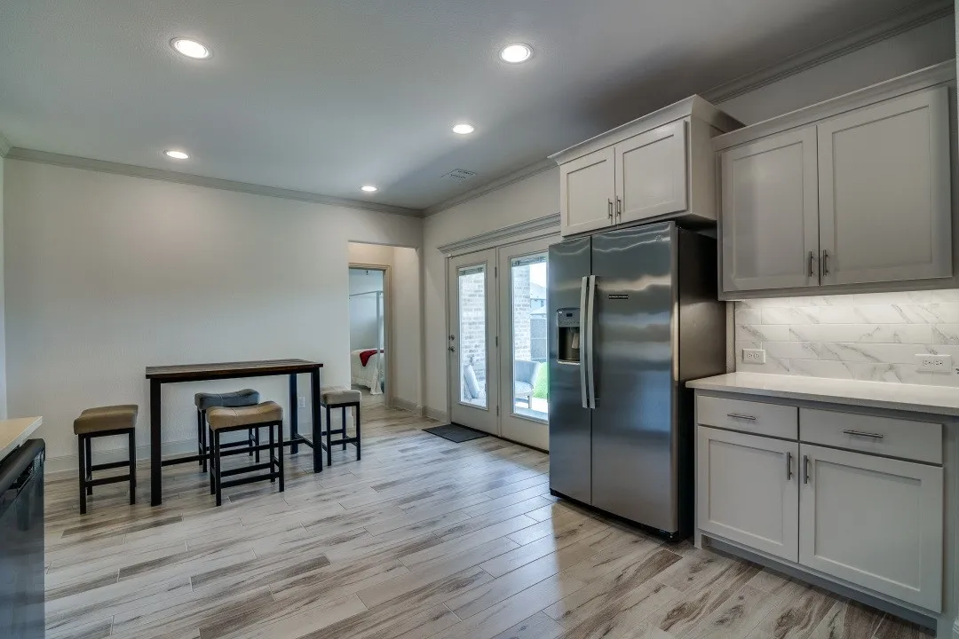 Kitchen featuring wood-finish flooring, recessed lighting, stainless steel refrigerator, light-colored cabinetry, and glass patio doors