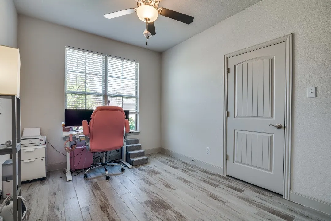 Wood-finish flooring, ceiling fan with integrated lighting, window with blinds, and a paneled interior door