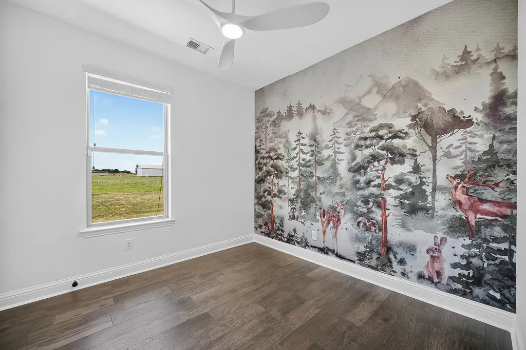Wood-finish flooring with white baseboards, a single window, and a ceiling fan with integrated lighting