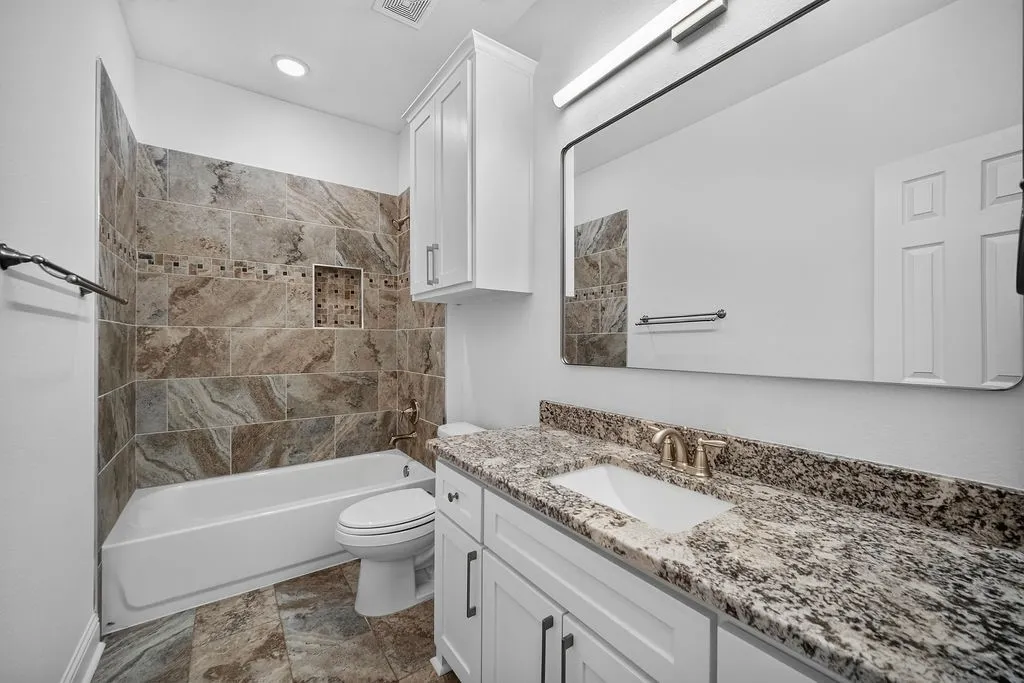Bathroom featuring a white vanity with a granite-look countertop, undermount sink, and white cabinetry