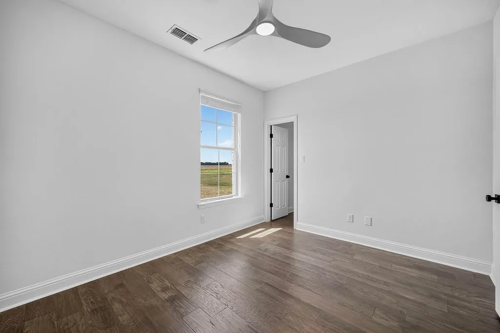 Wood-finish flooring, white walls, modern ceiling fan, white trim, and a clear pane window