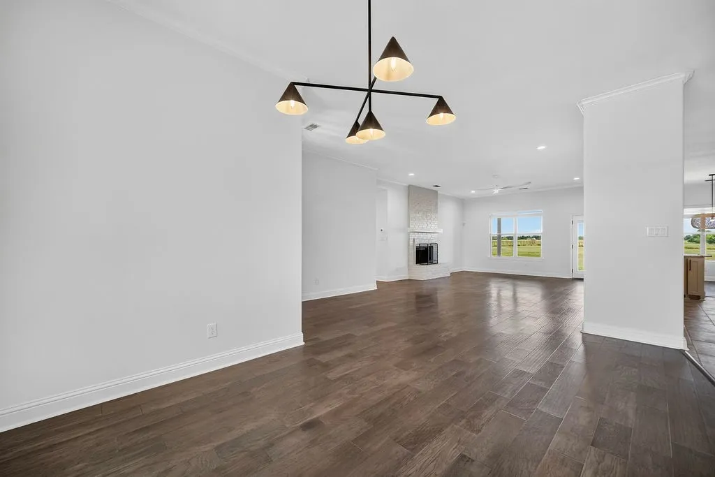Wood-finish flooring, contemporary chandelier, tiled fireplace, crown molding, and recessed lighting