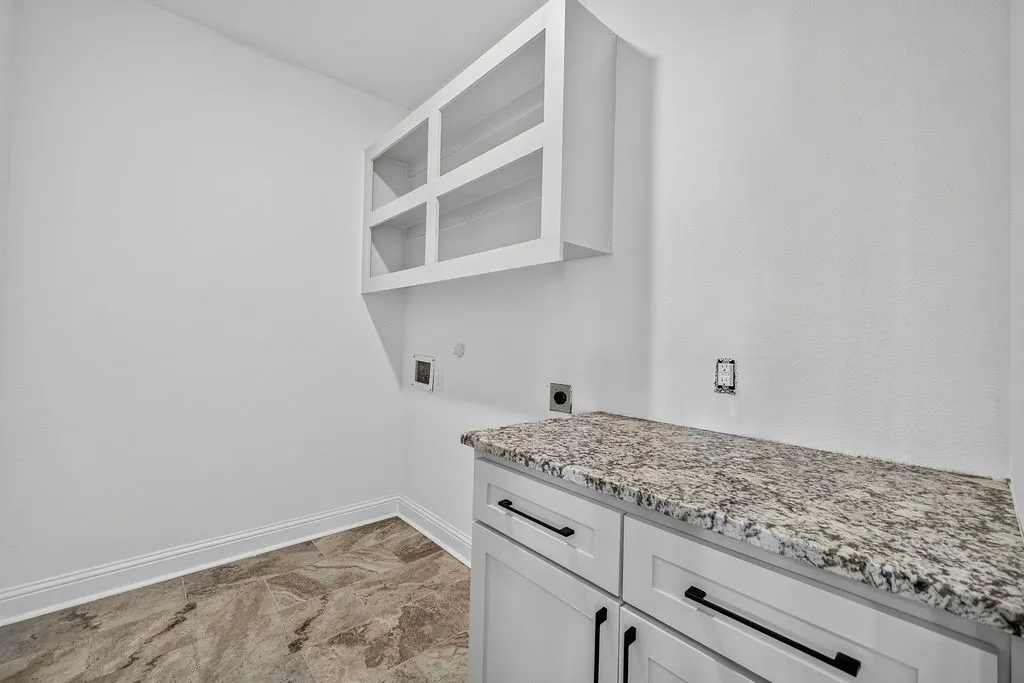 White shaker cabinetry with black hardware, stone countertop, upper glass-front cabinetry, and wood-finish flooring