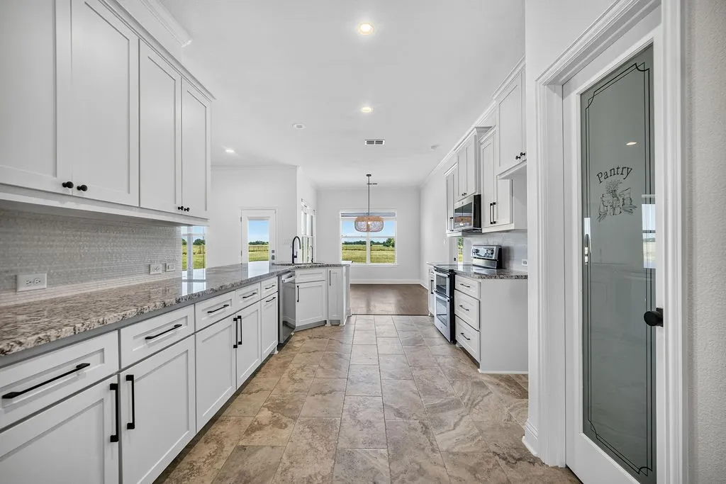 Kitchen featuring white shaker cabinetry, granite countertops, stainless steel appliances, a tile backsplash, and a frosted glass pantry door