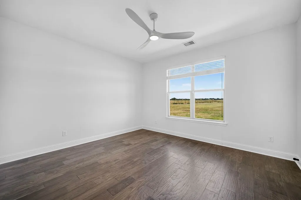 Wood-finish flooring, white walls, modern ceiling fan, and a large window