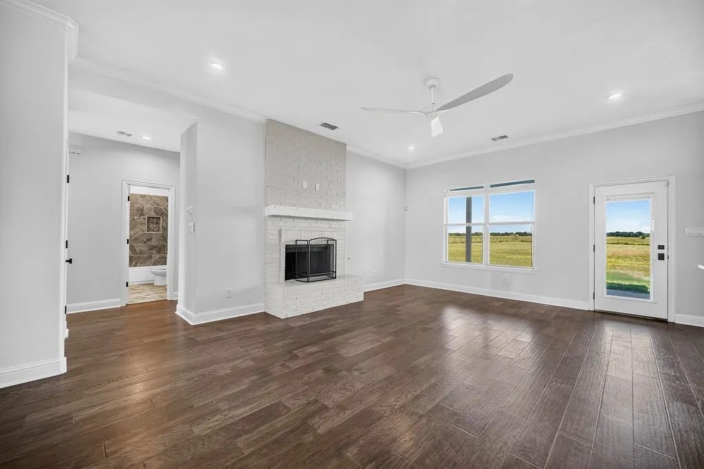 Spacious living area featuring wood-finish flooring, a white brick fireplace, a ceiling fan, and recessed lighting