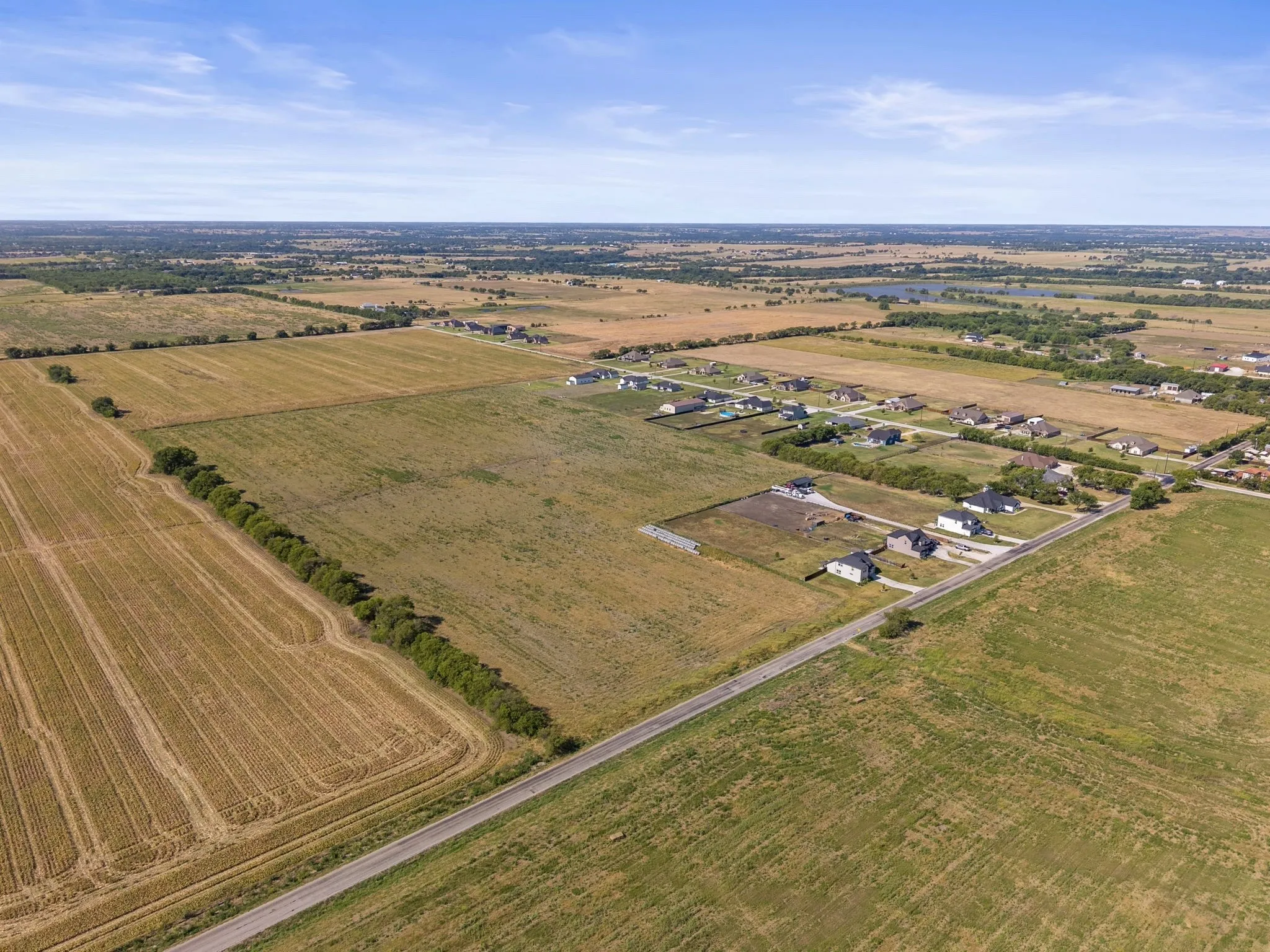 Expansive open land with cultivated fields and a paved road