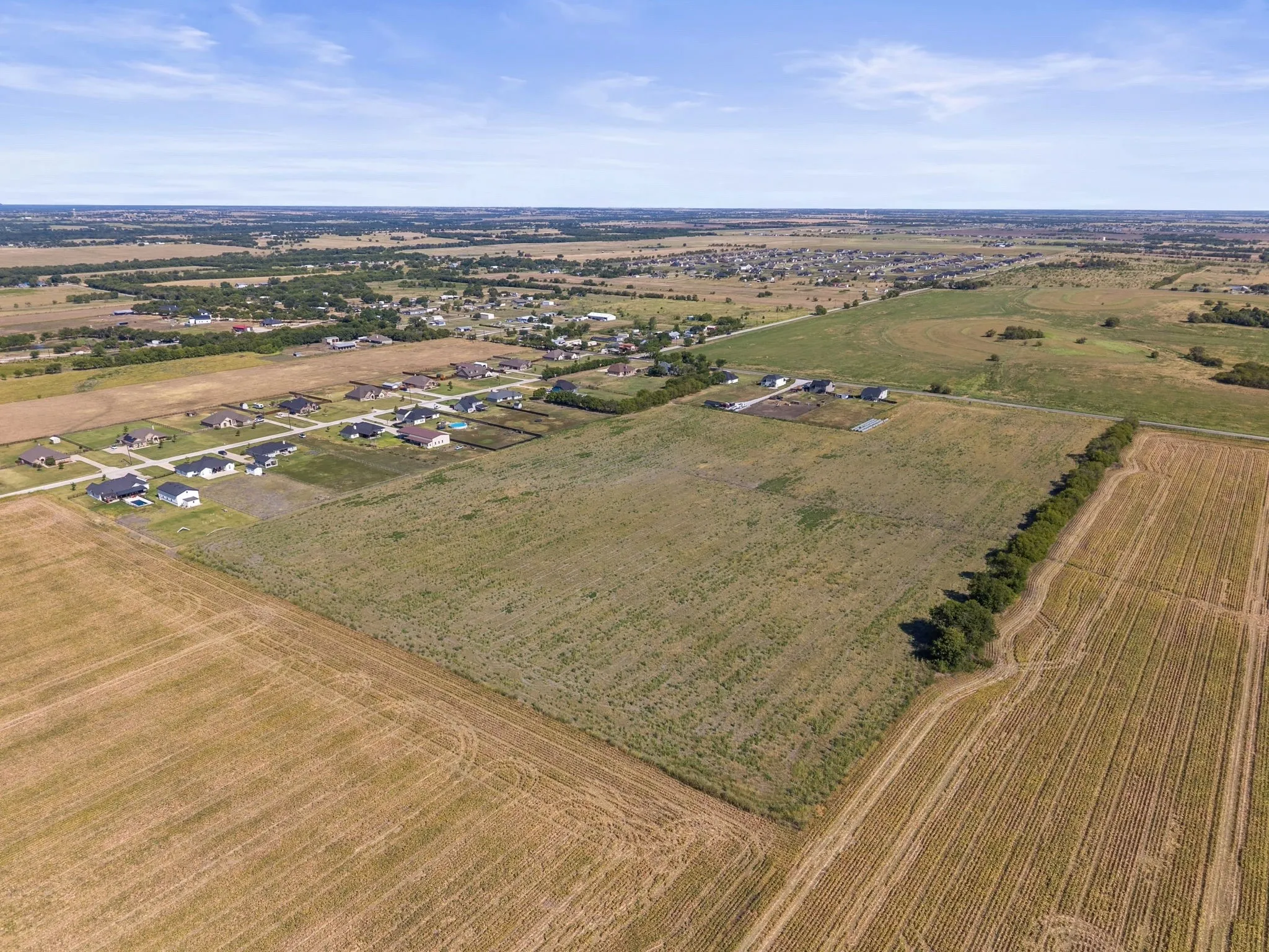 Expansive parcel featuring open fields and established residential areas nearby