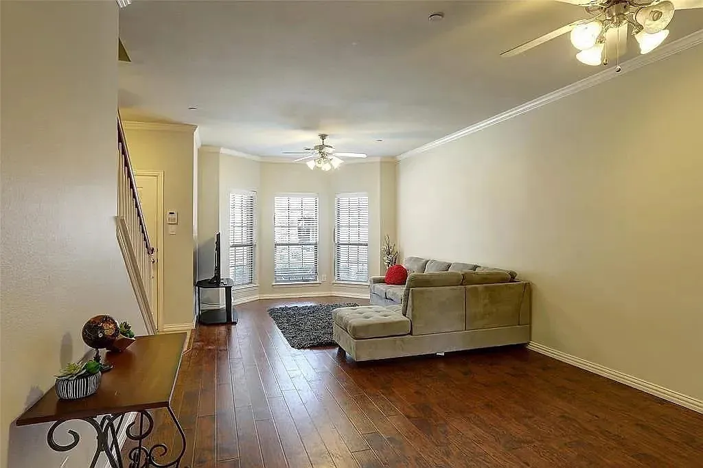 Living room featuring ornamental molding, dark wood-style floors, baseboards, and ceiling fan
