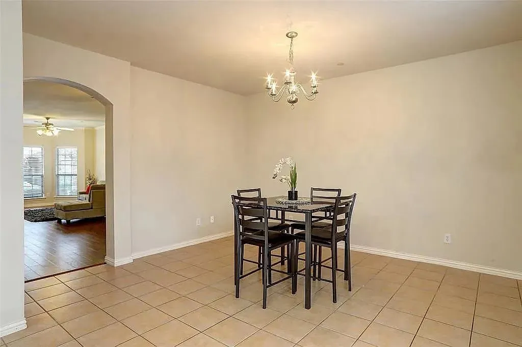 Dining room with arched walkways, ceiling fan with notable chandelier, baseboards, and light tile patterned flooring