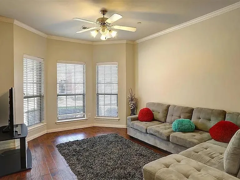 Living room featuring baseboards, a ceiling fan, dark wood-style flooring, and crown molding