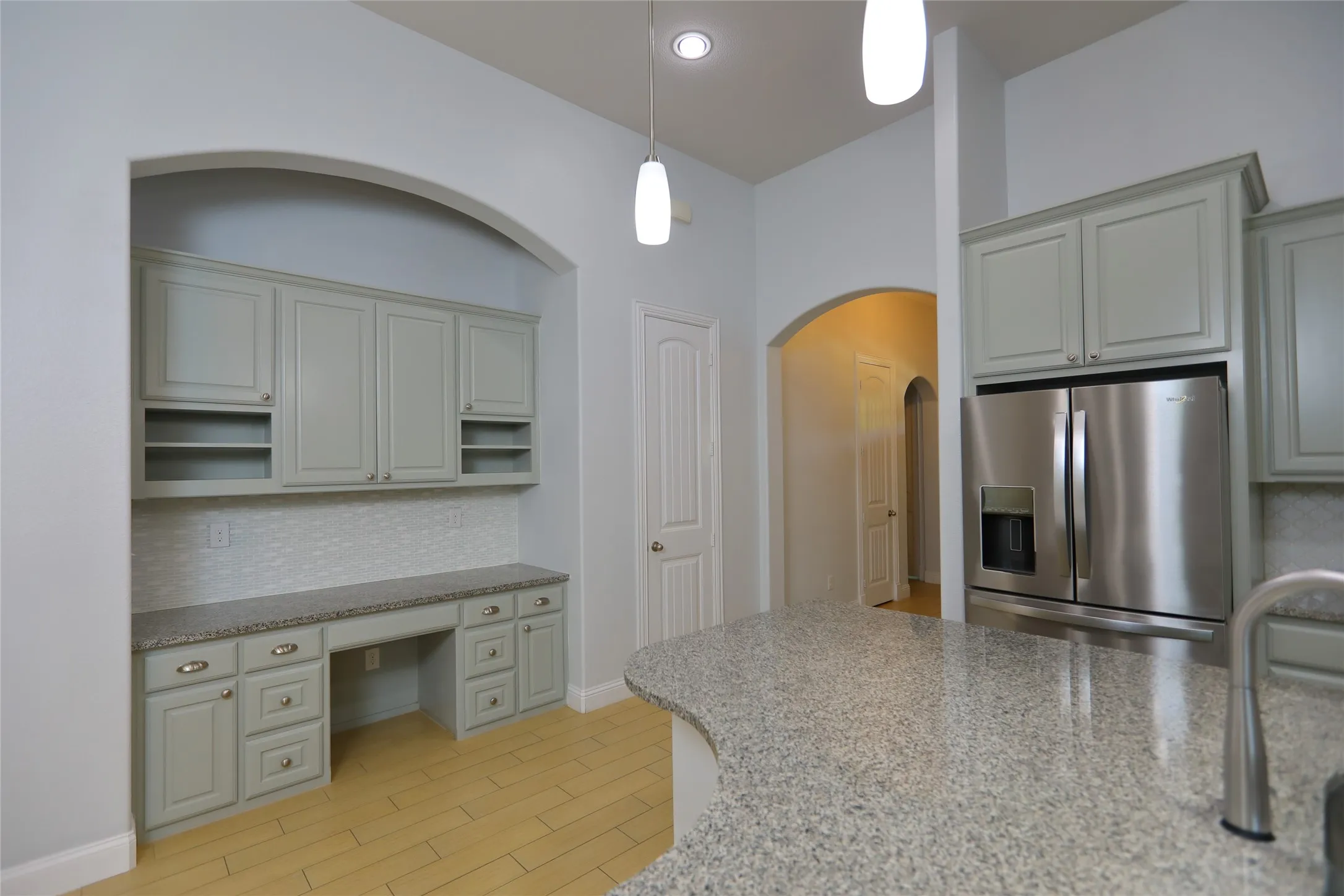 Built-in desk area with light gray cabinetry, a mosaic tile backsplash, and a light-colored countertop