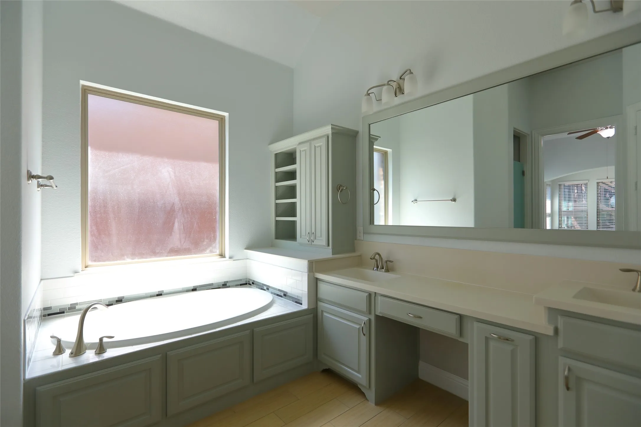 Soaking tub with a tiled surround, complemented by a window and integrated cabinetry
