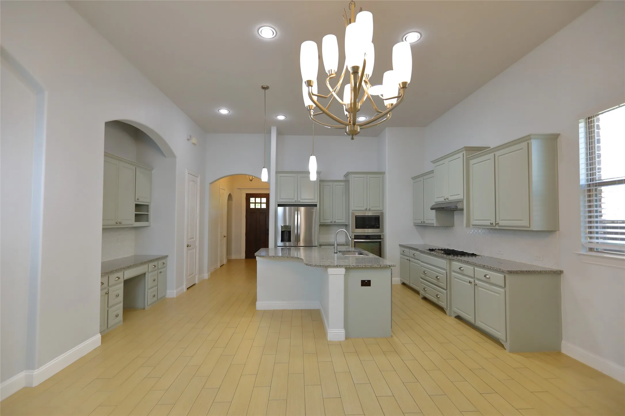 Expansive kitchen and living area featuring wood-finish flooring, recessed lighting, and a contemporary chandelier