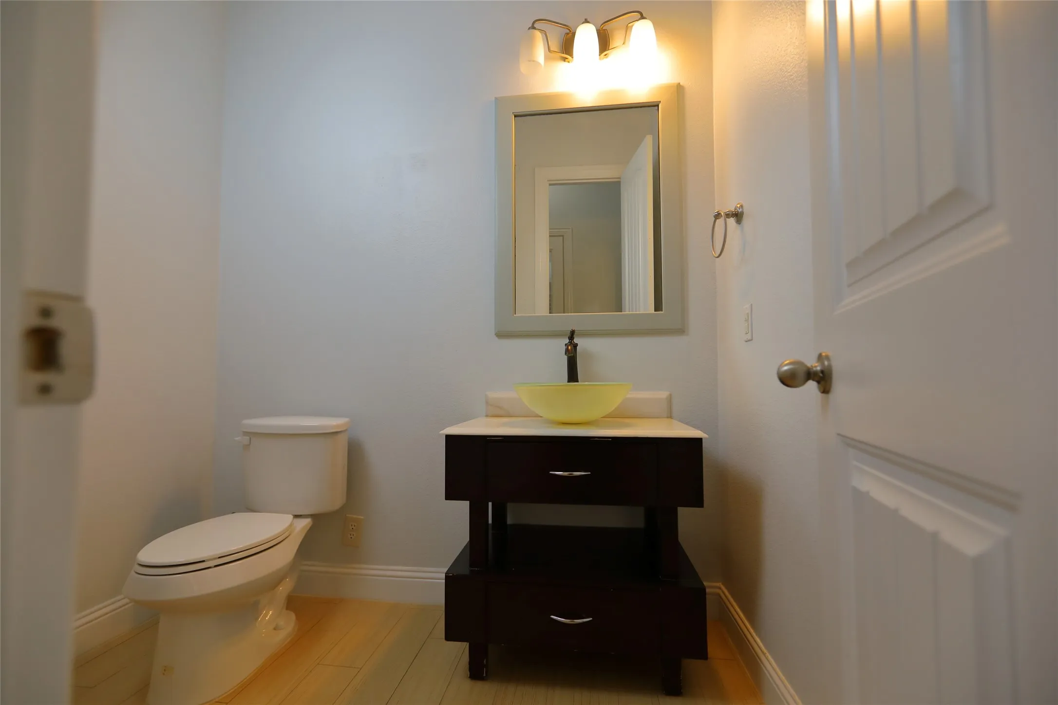 Modern vanity with an amber vessel sink, dark wood-finish cabinetry, and a light-toned countertop