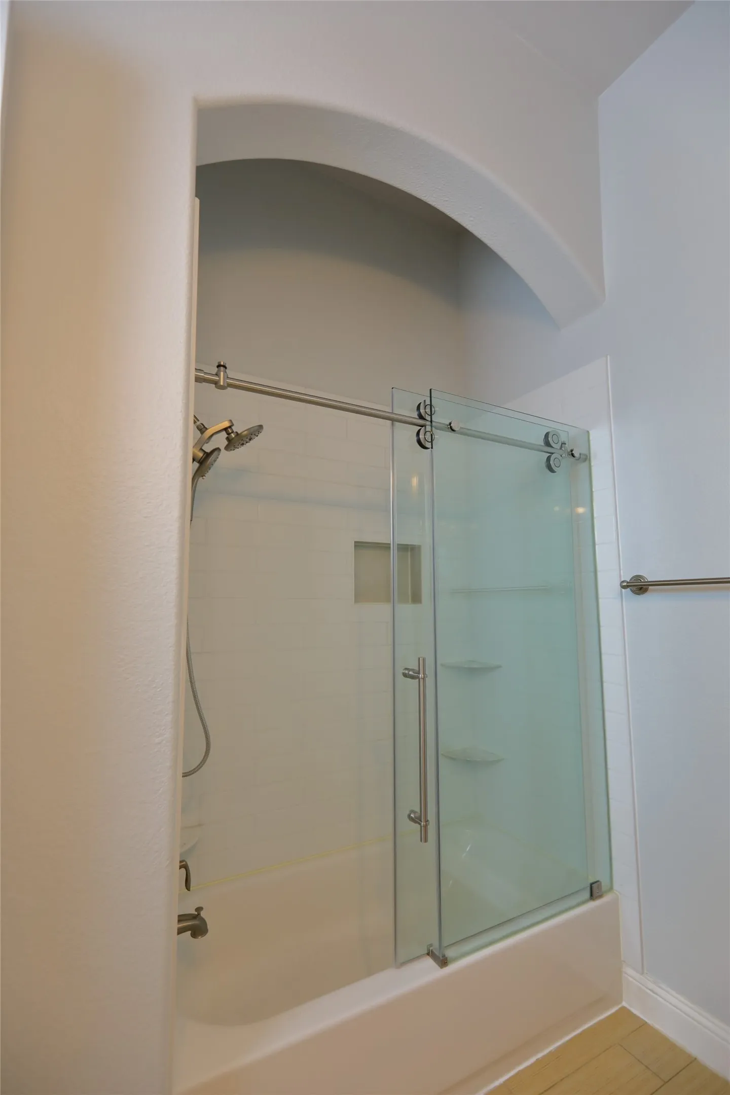 Bathtub with white subway tile surround, recessed shelf, and built-in shelving