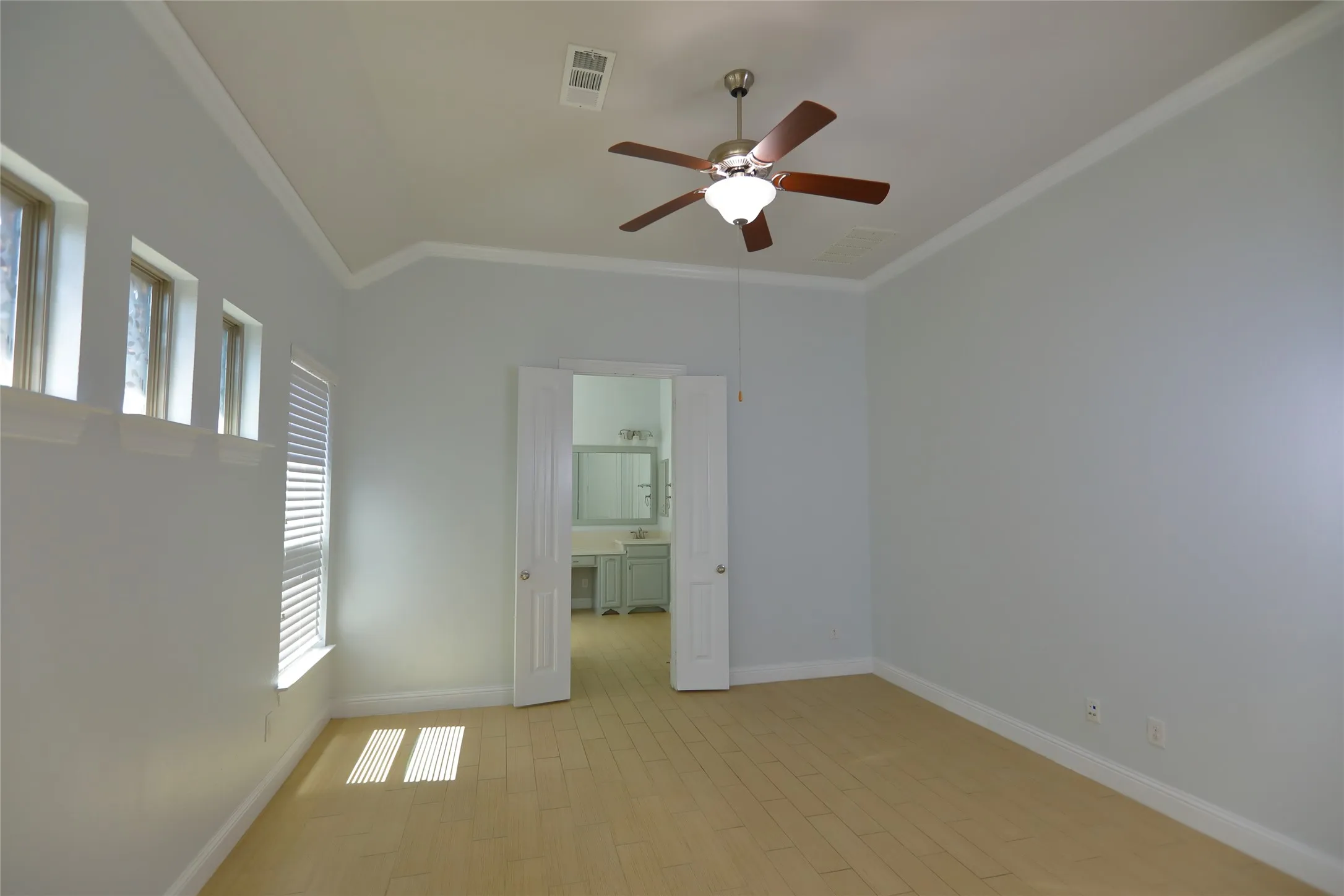 Spacious interior room featuring wood-finish flooring, vaulted ceiling, and crown molding