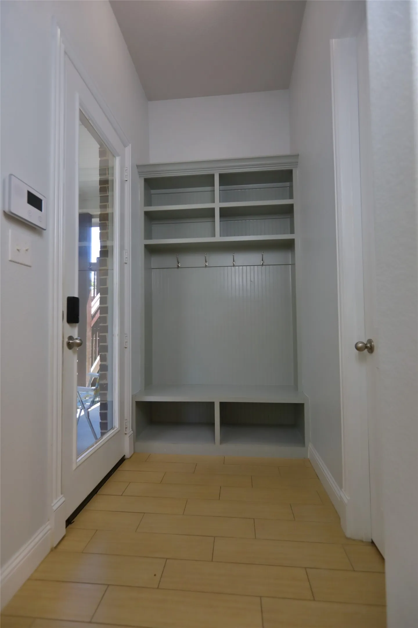 Entryway featuring a built-in storage unit with upper shelving, coat hooks, and integrated bench seating
