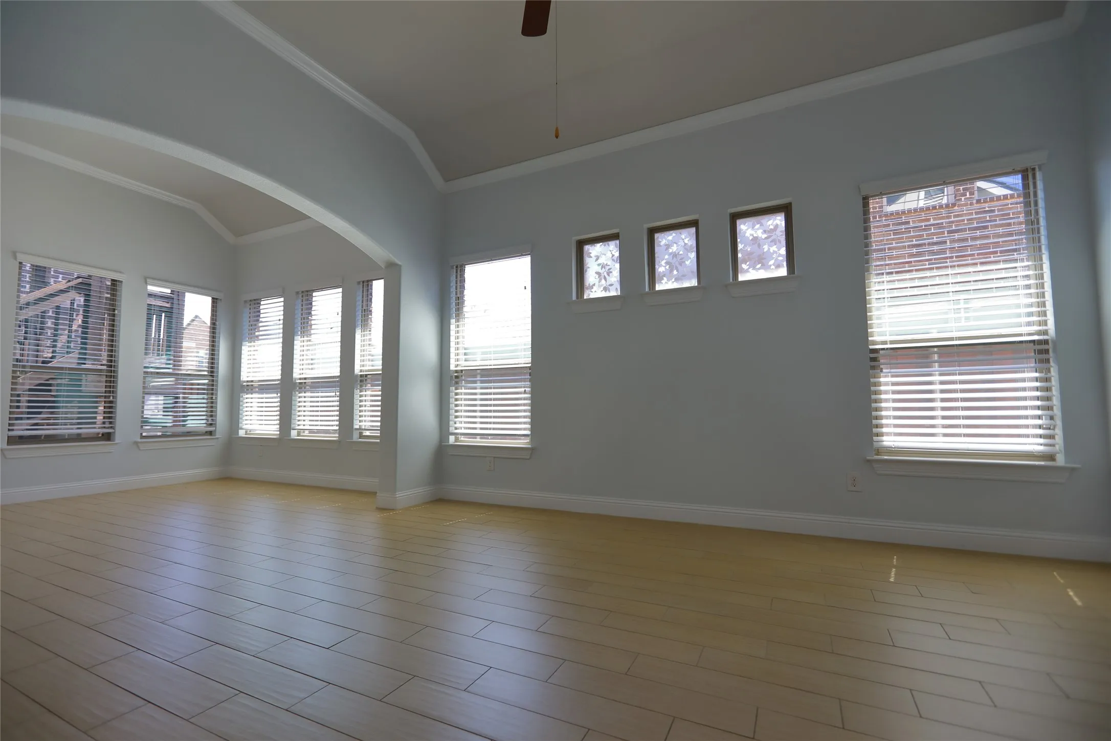 Spacious interior with vaulted ceilings, light wood-finish flooring, and crown molding