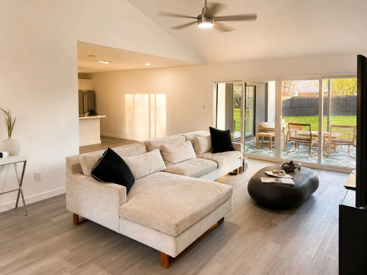 Vaulted ceilings, wood-finish flooring, ceiling fan, and sliding glass doors leading to an outdoor patio