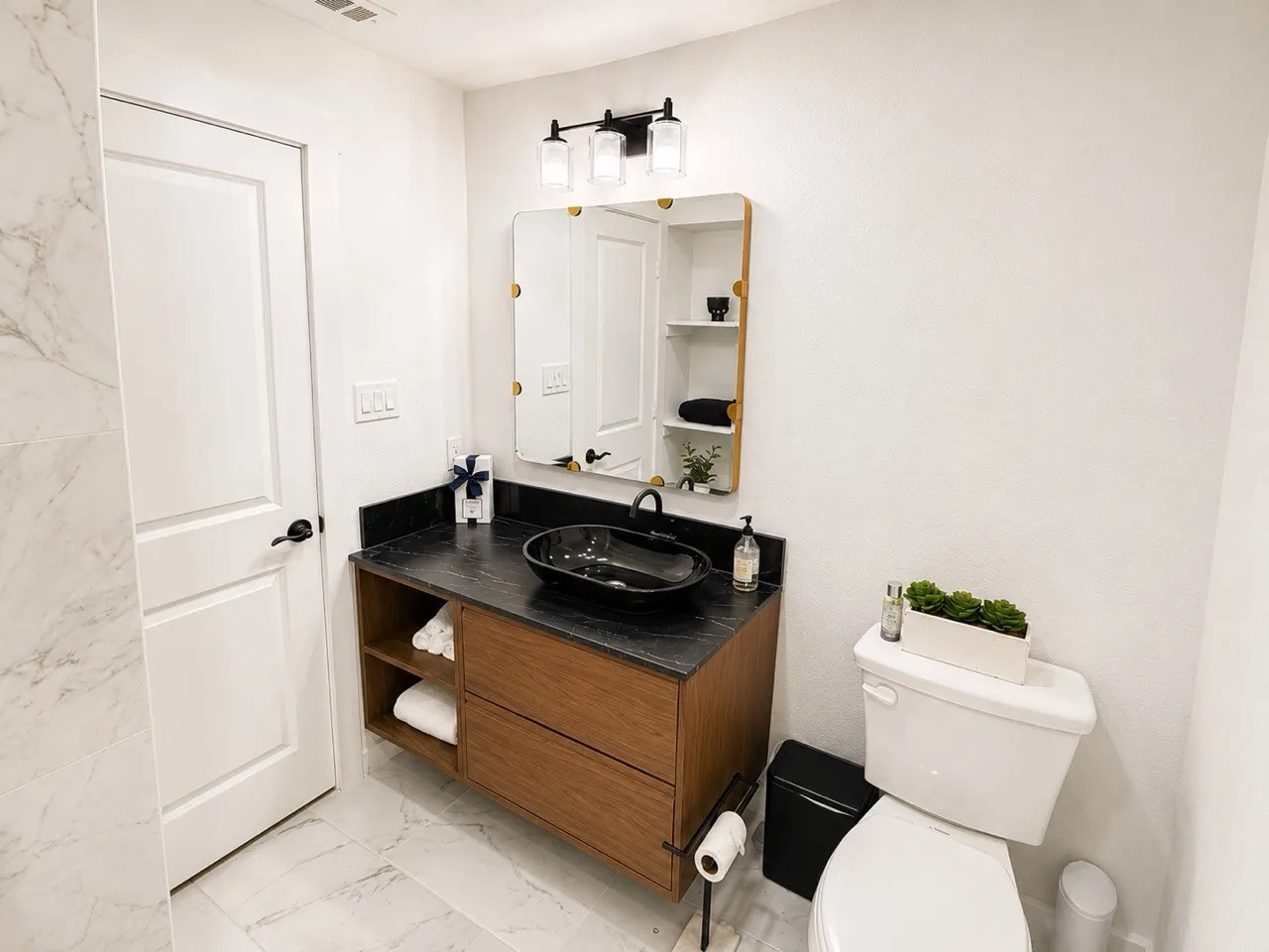 Modern vanity with a dark countertop and vessel sink, illuminated by a three-light fixture