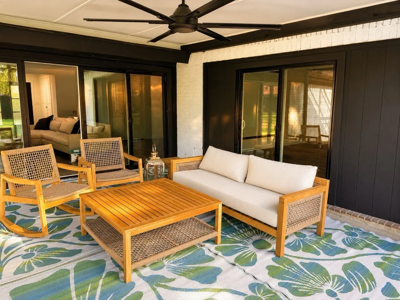 Covered patio featuring a ceiling fan, brick wall, and dark-framed sliding glass doors