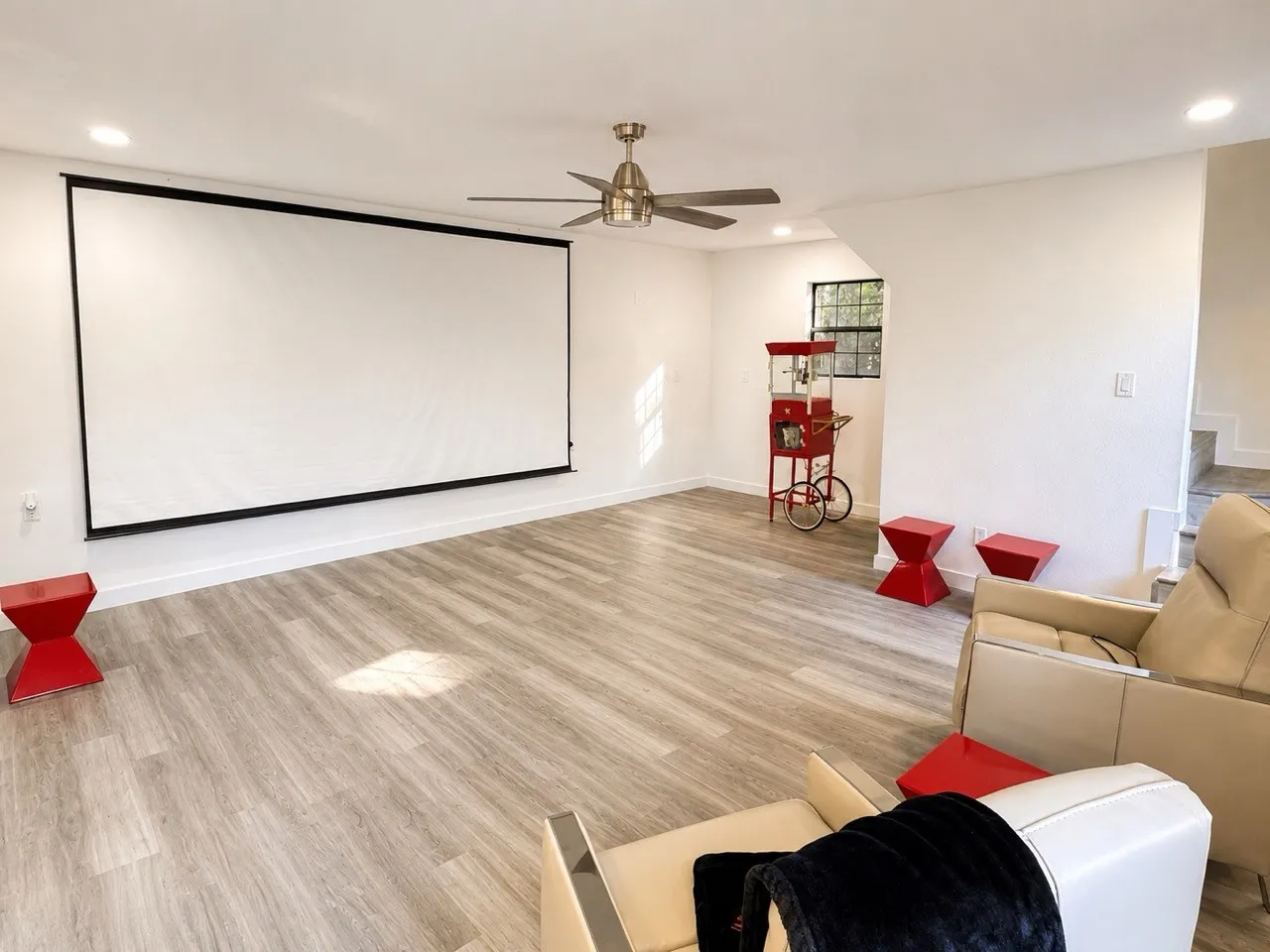 Projector screen with recessed lighting, wood-finish flooring, and a ceiling fan