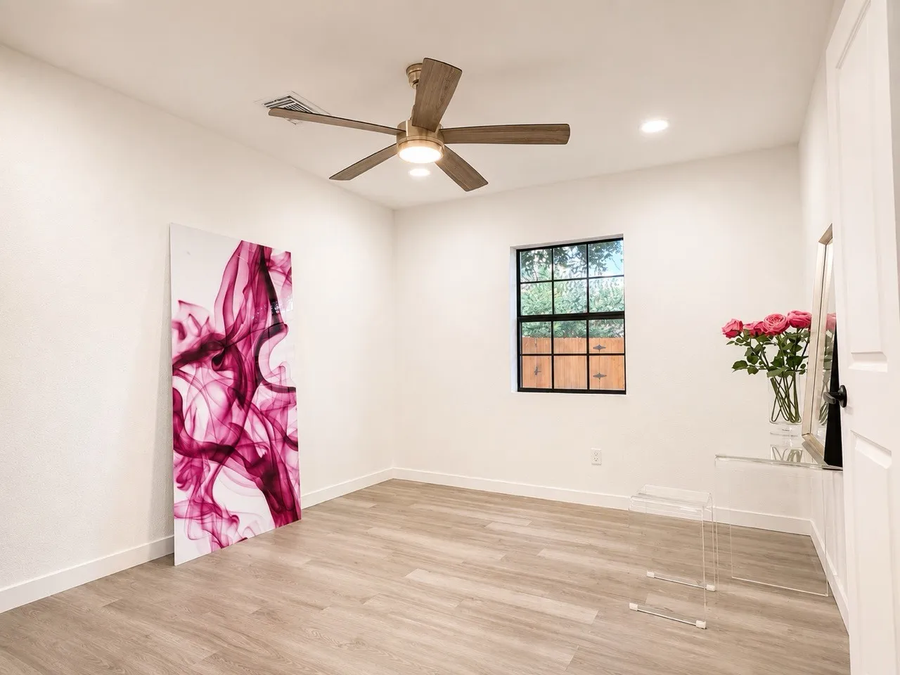 Wood-finish flooring, recessed lighting, ceiling fan with integrated light, and a window with black grilles