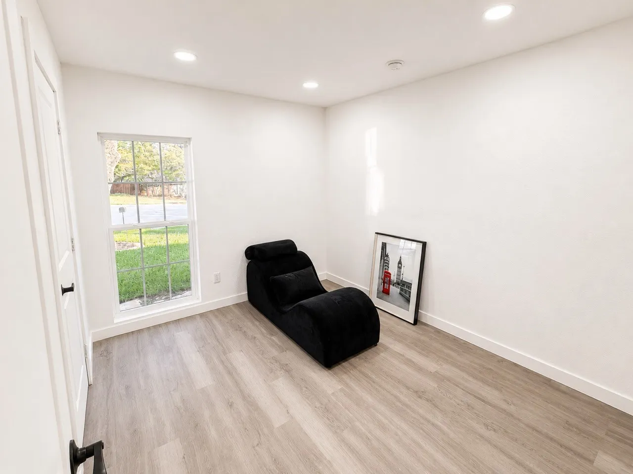 Recessed lighting, wood-finish flooring, white walls, and a window with natural light