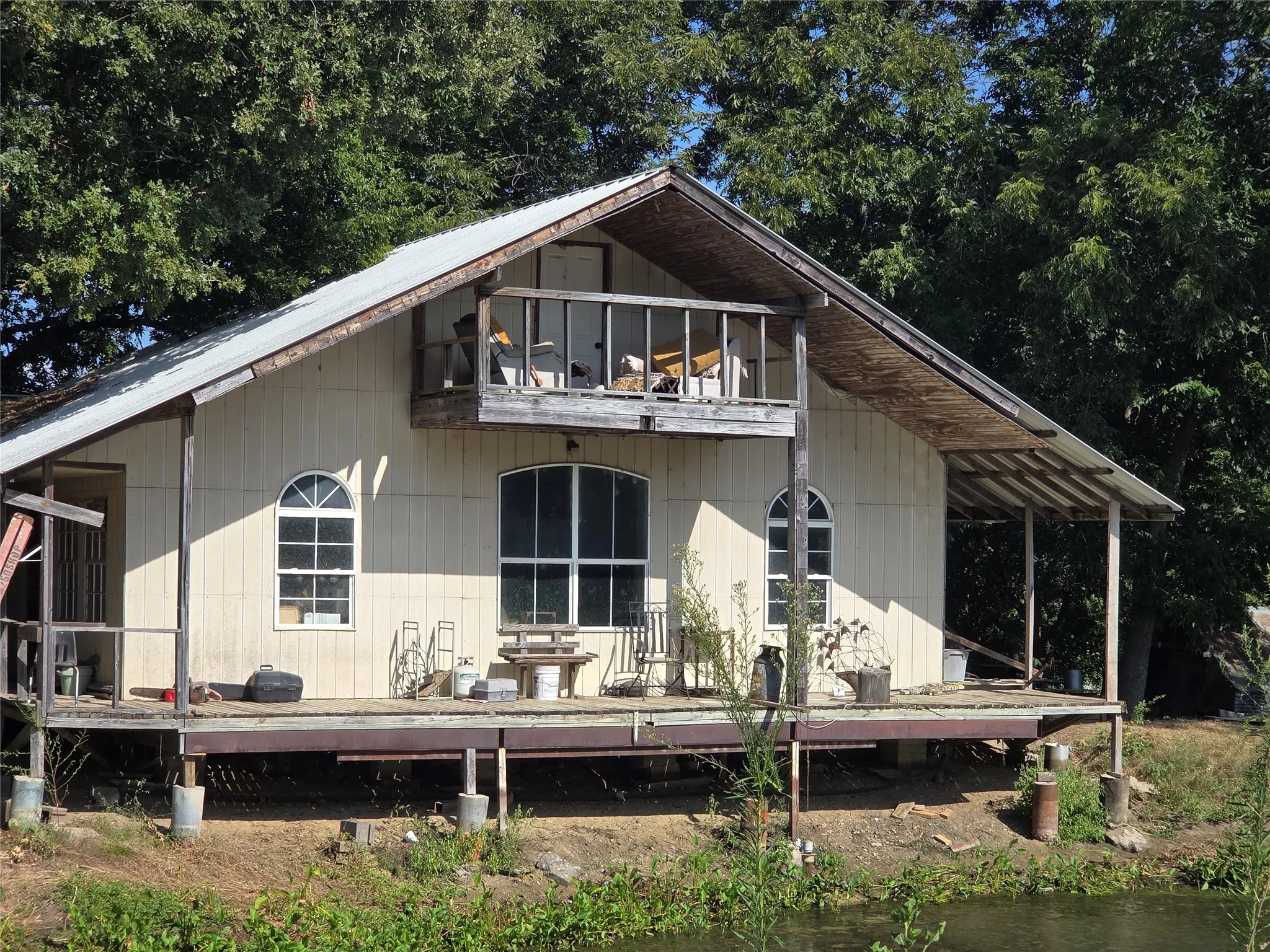 Exterior featuring multiple windows, an arched window, a covered porch, and an upper-level balcony
