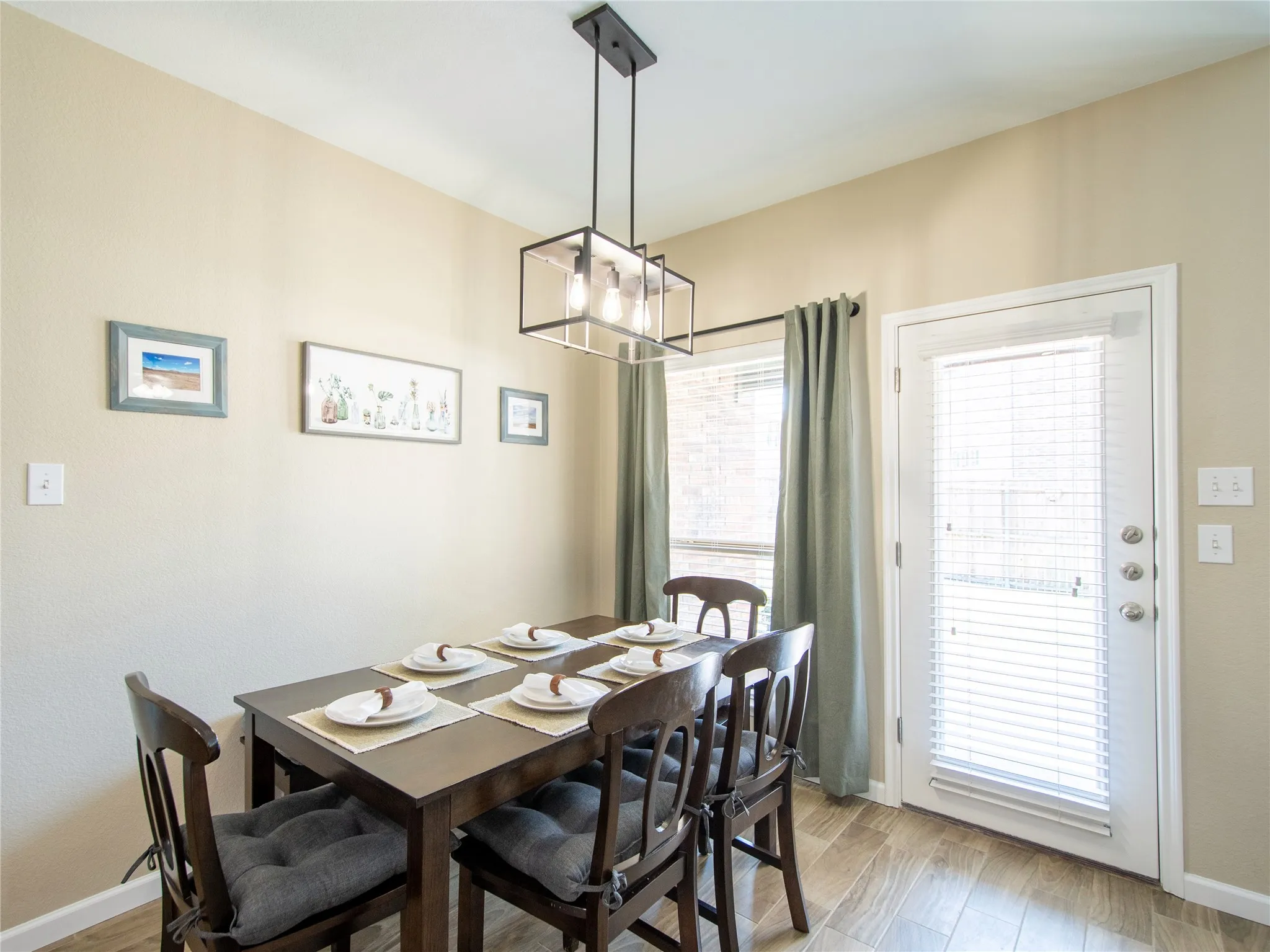 Dining area with neutral wall paint, wood-finish flooring, and a modern linear pendant light fixture