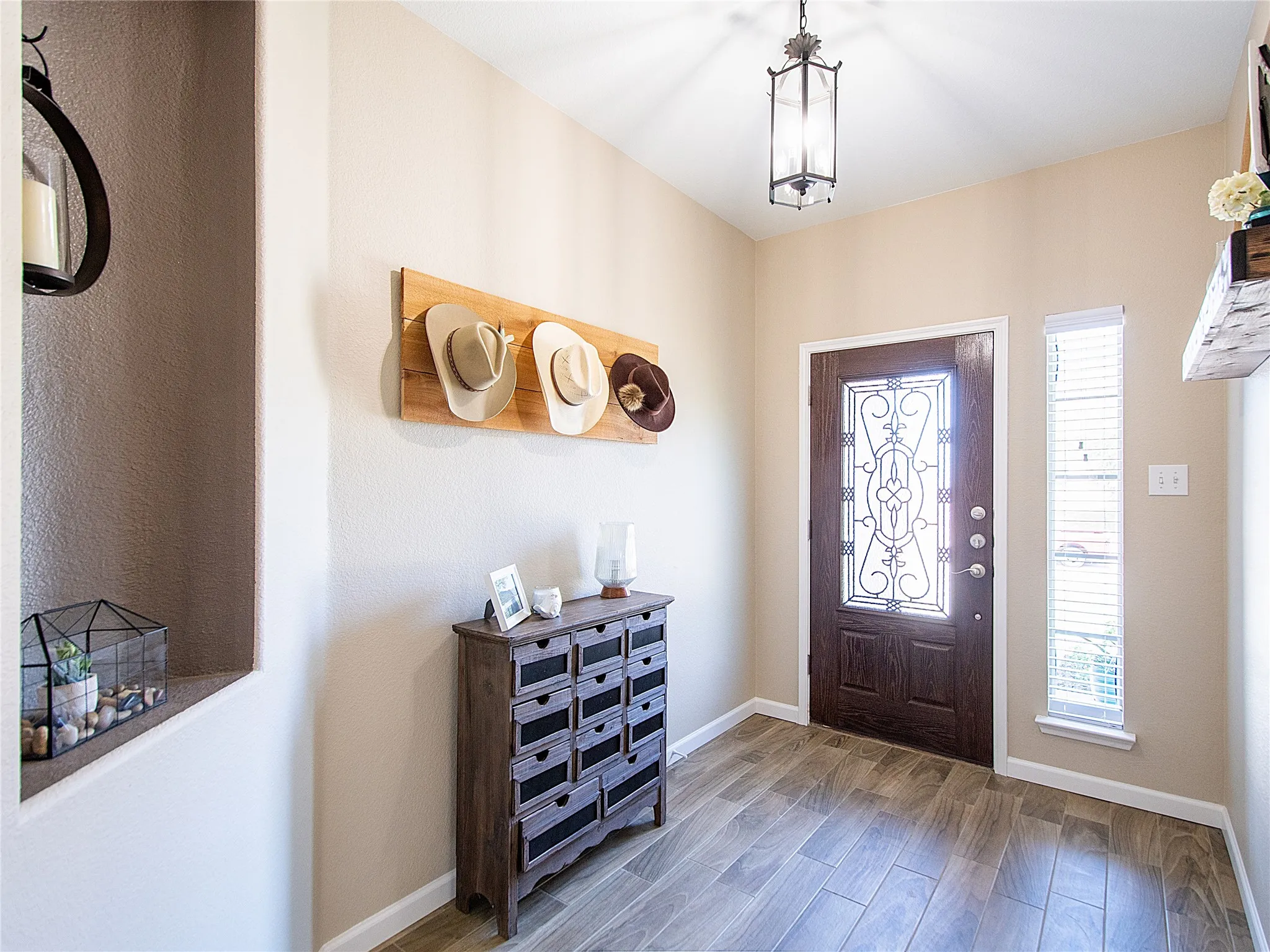 Wood-finish tile flooring, recessed wall niche, and an ornate dark wood entry door with decorative glass inlay