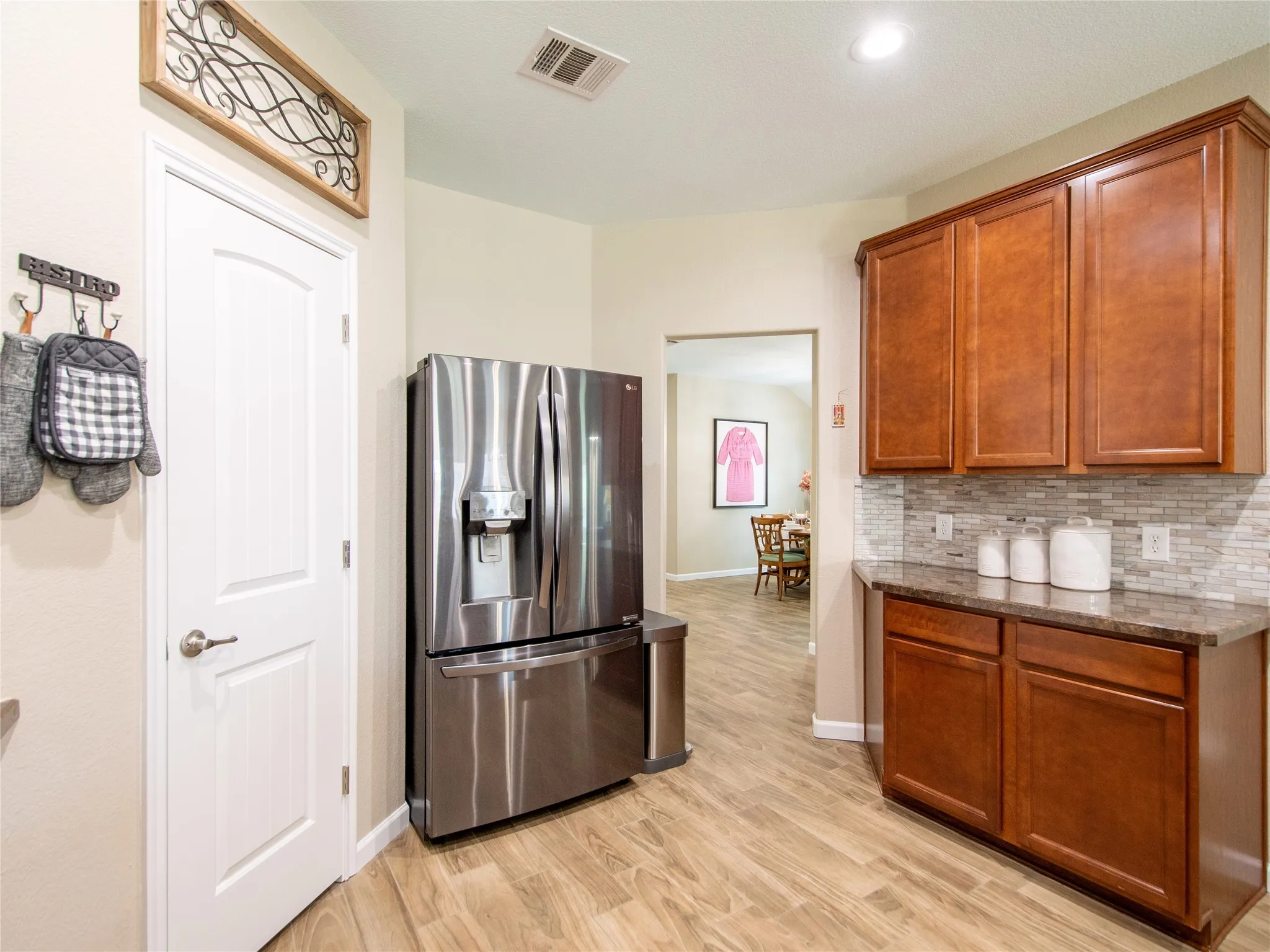Wood-finish flooring, recessed lighting, built-in wood cabinetry, mosaic tile backsplash, and dark countertop