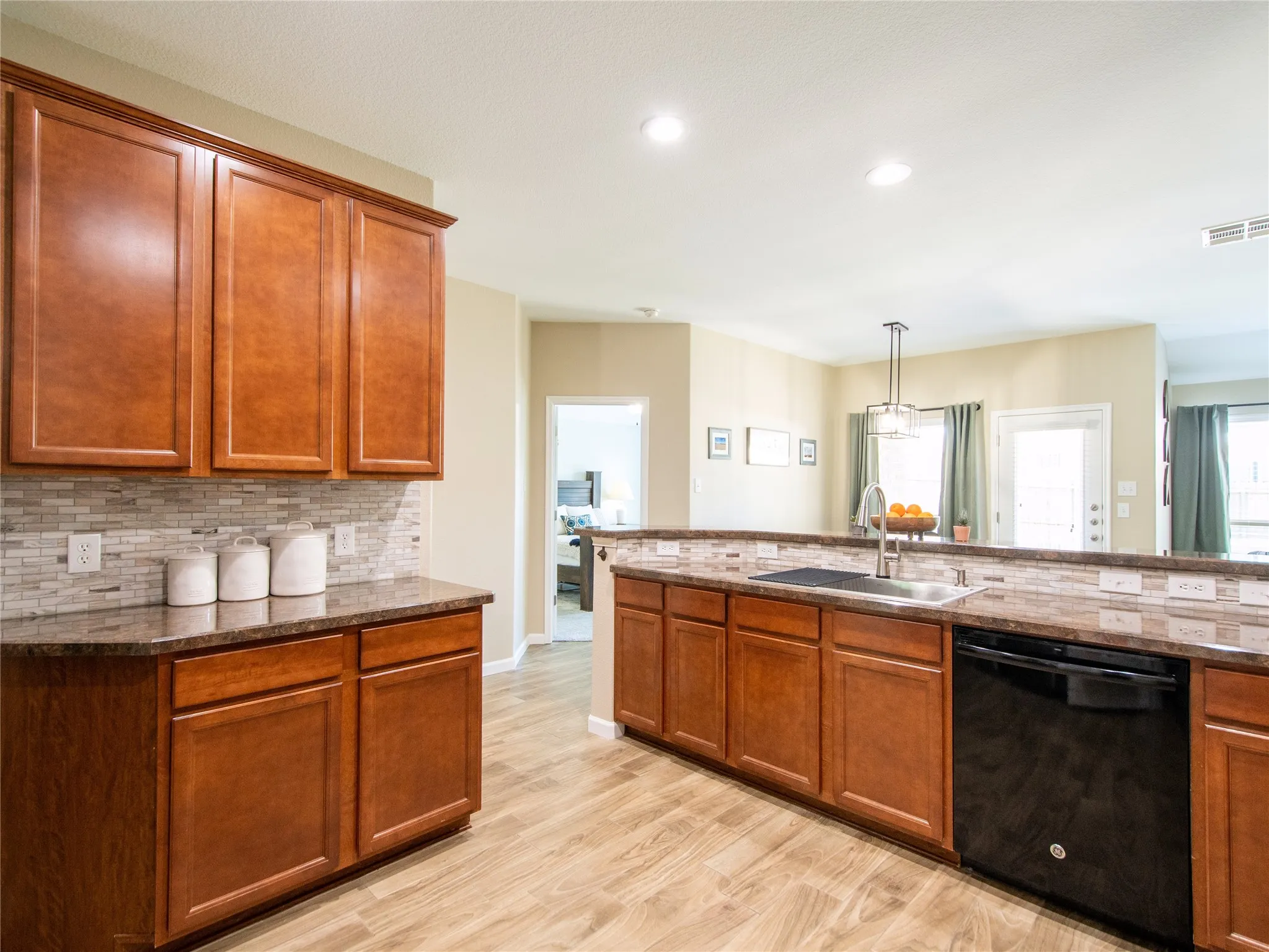 Spacious kitchen featuring rich wood cabinetry, stainless steel appliances, and dual islands with wood-finish flooring throughout