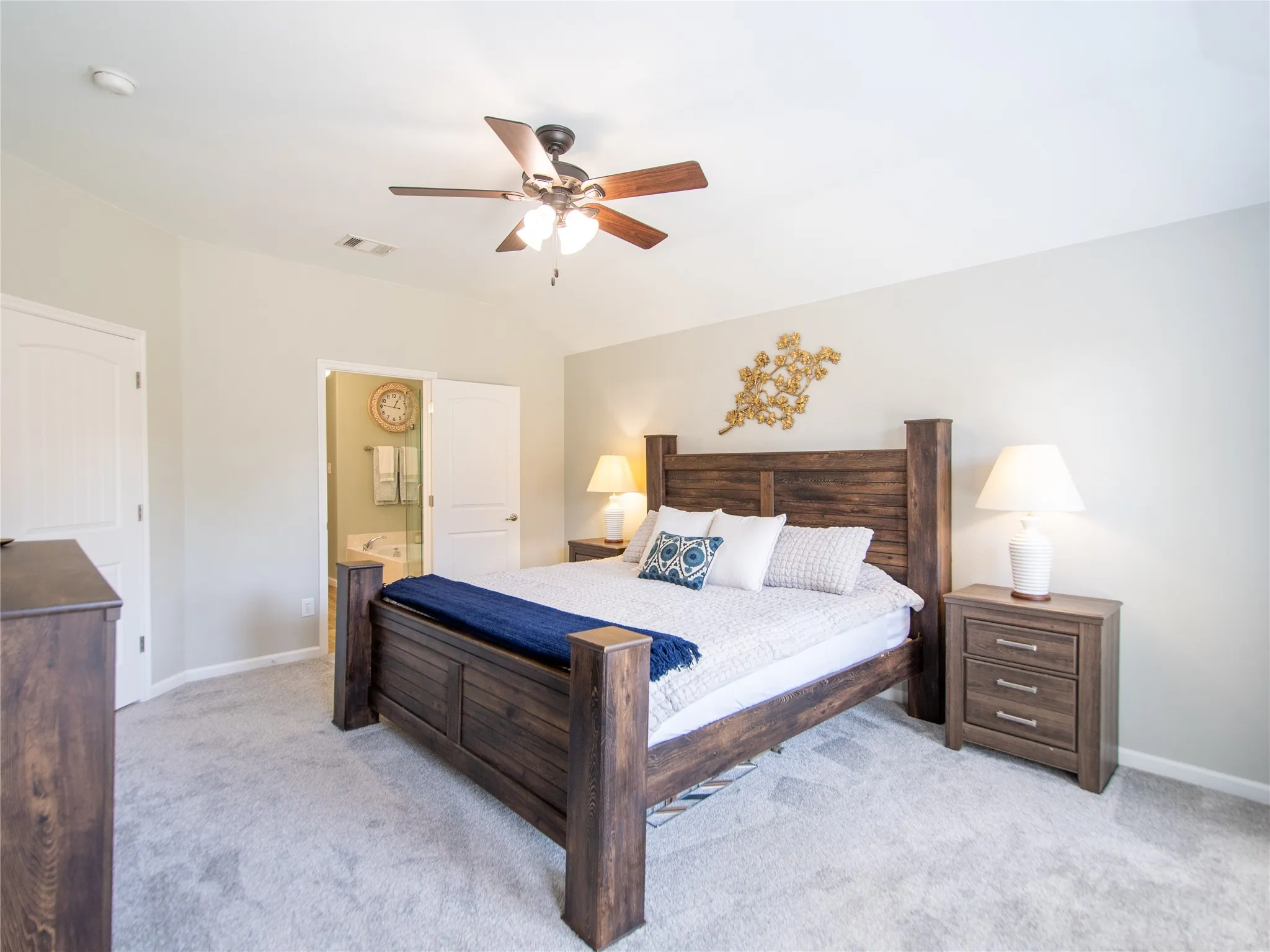 Primary with ensuite bath. Carpeted flooring, vaulted ceiling, and a ceiling fan with integrated lighting