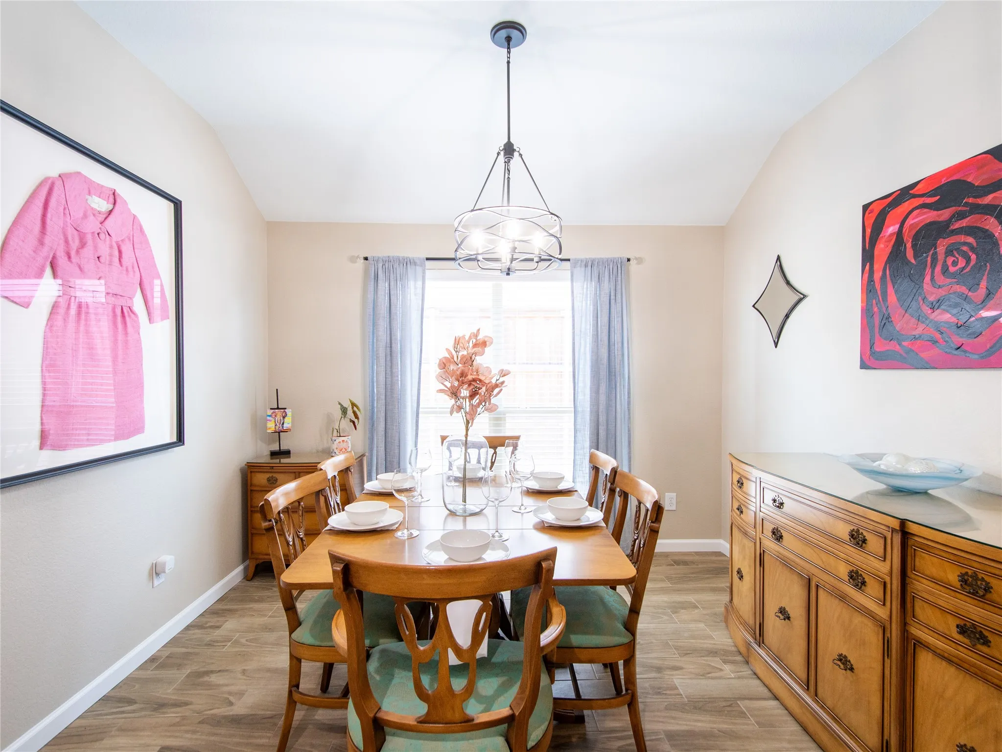 Vaulted ceiling with a contemporary chandelier, wood-finish flooring, and window with natural light