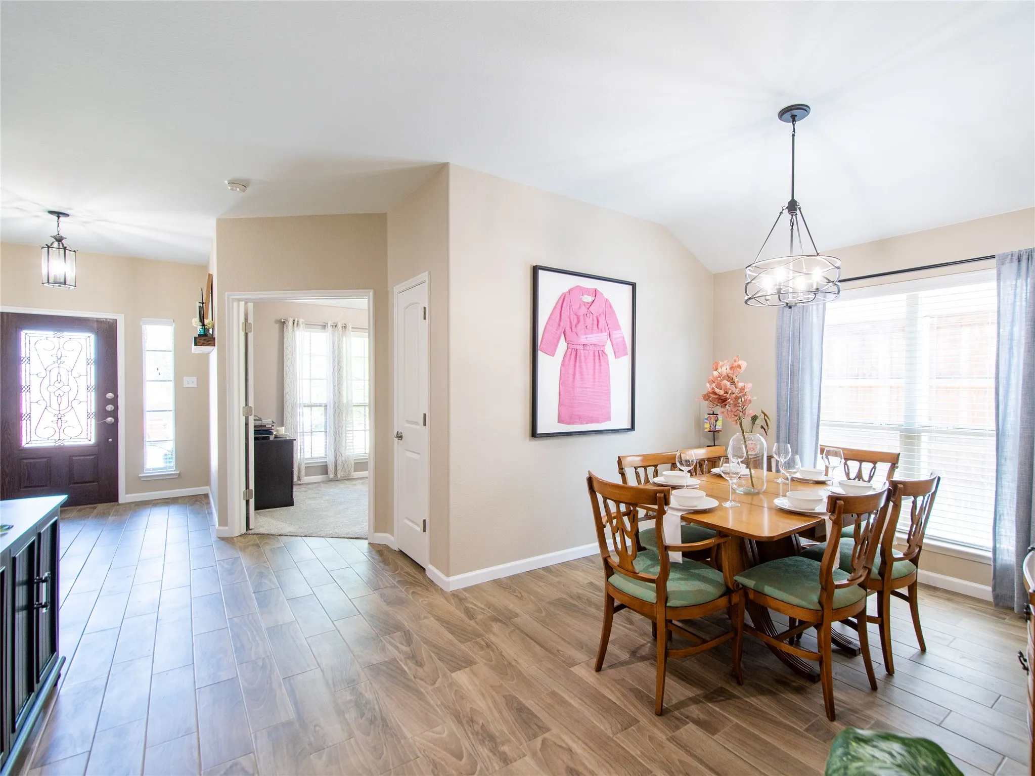 Wood-finish flooring throughout, decorative front entry door, recessed lighting, and a contemporary dining room chandelier