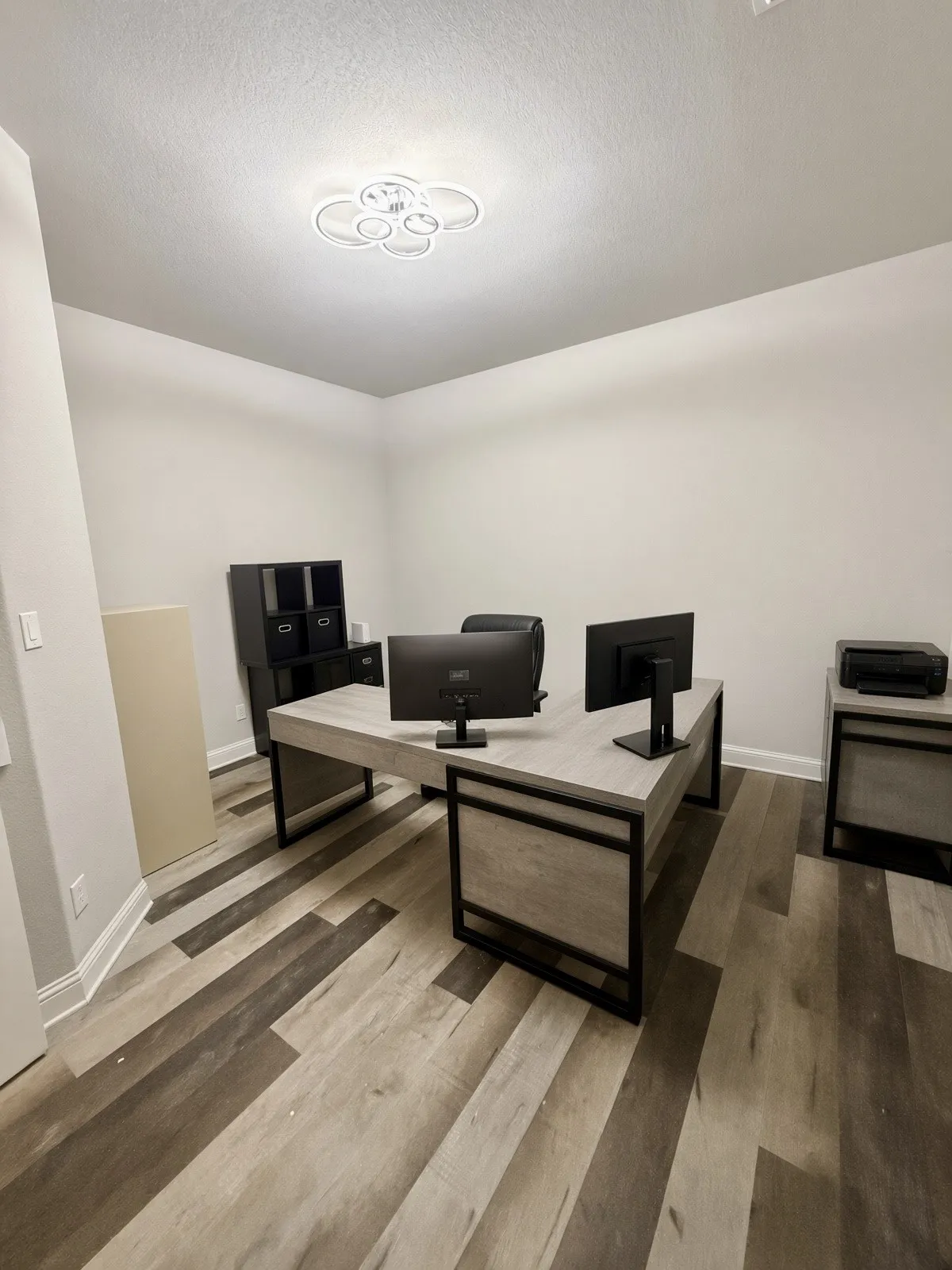 Multi-tone wood-finish flooring, white walls, and a contemporary ceiling light fixture