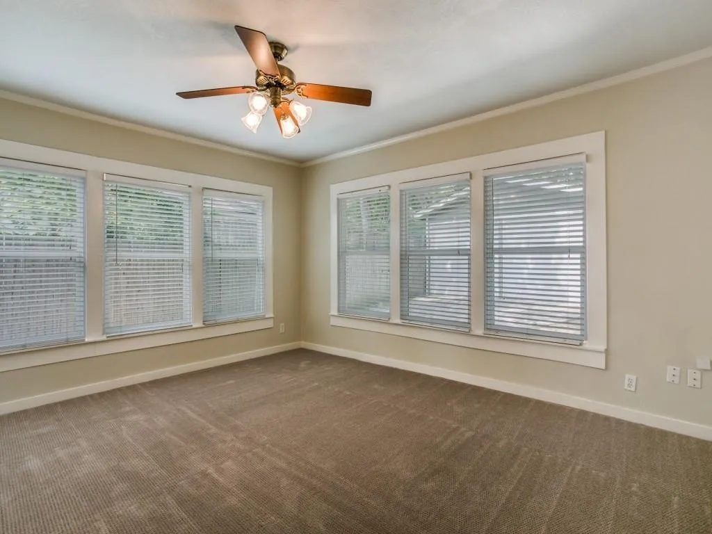 Textured carpeting, multiple windows with blinds, ceiling fan with integrated lighting, and neutral wall tones