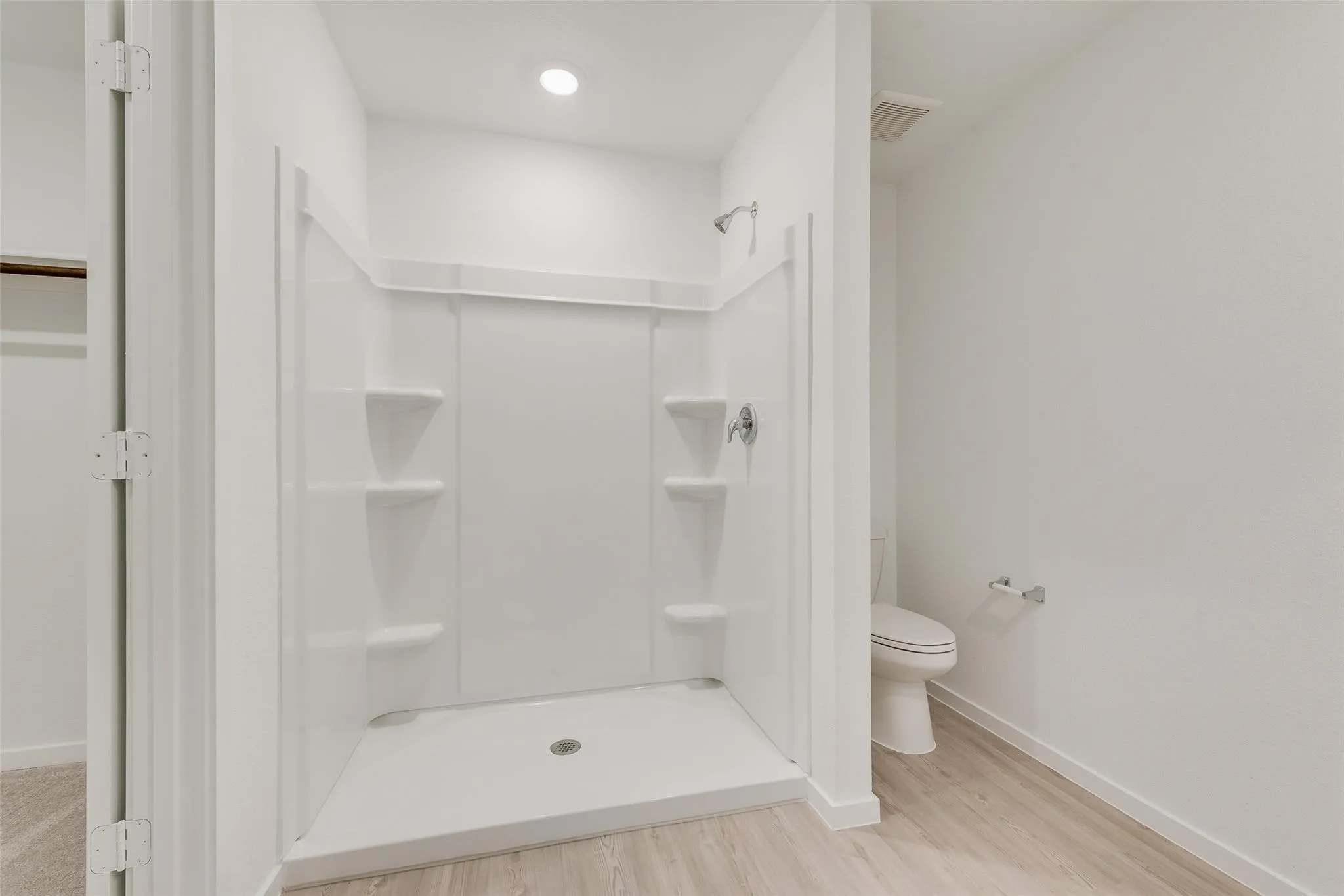 Walk-in shower with integrated shelving, chrome shower fixtures, and overhead recessed lighting