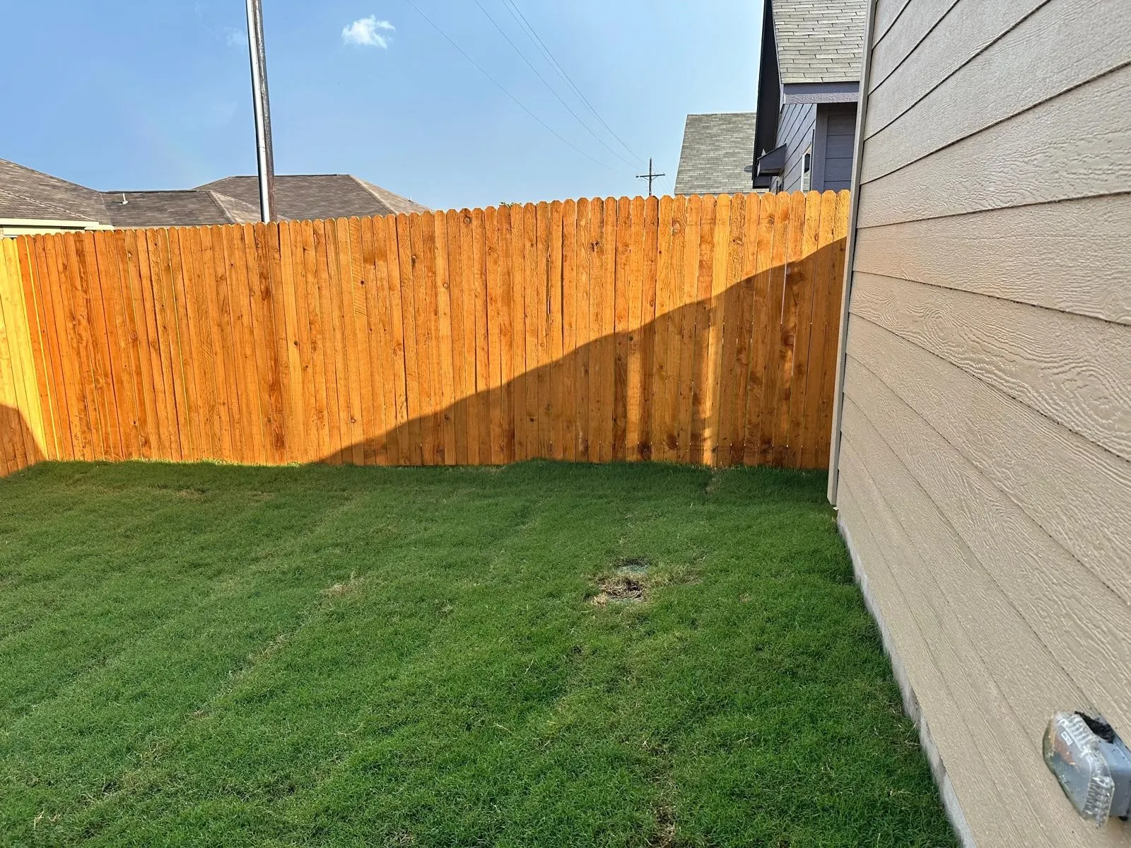 Lawn area featuring a wood privacy fence and horizontal siding