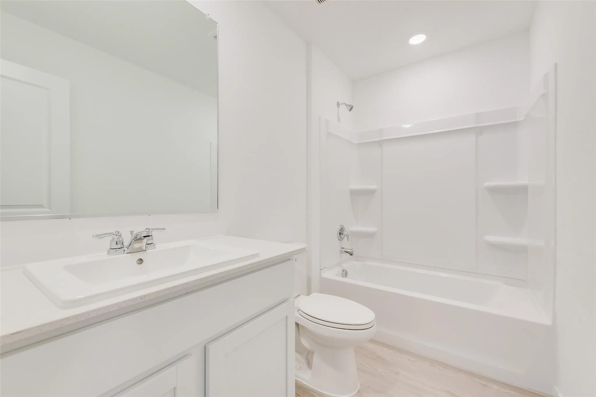 White vanity with a rectangular undermount sink, chrome faucet, and light-toned countertop