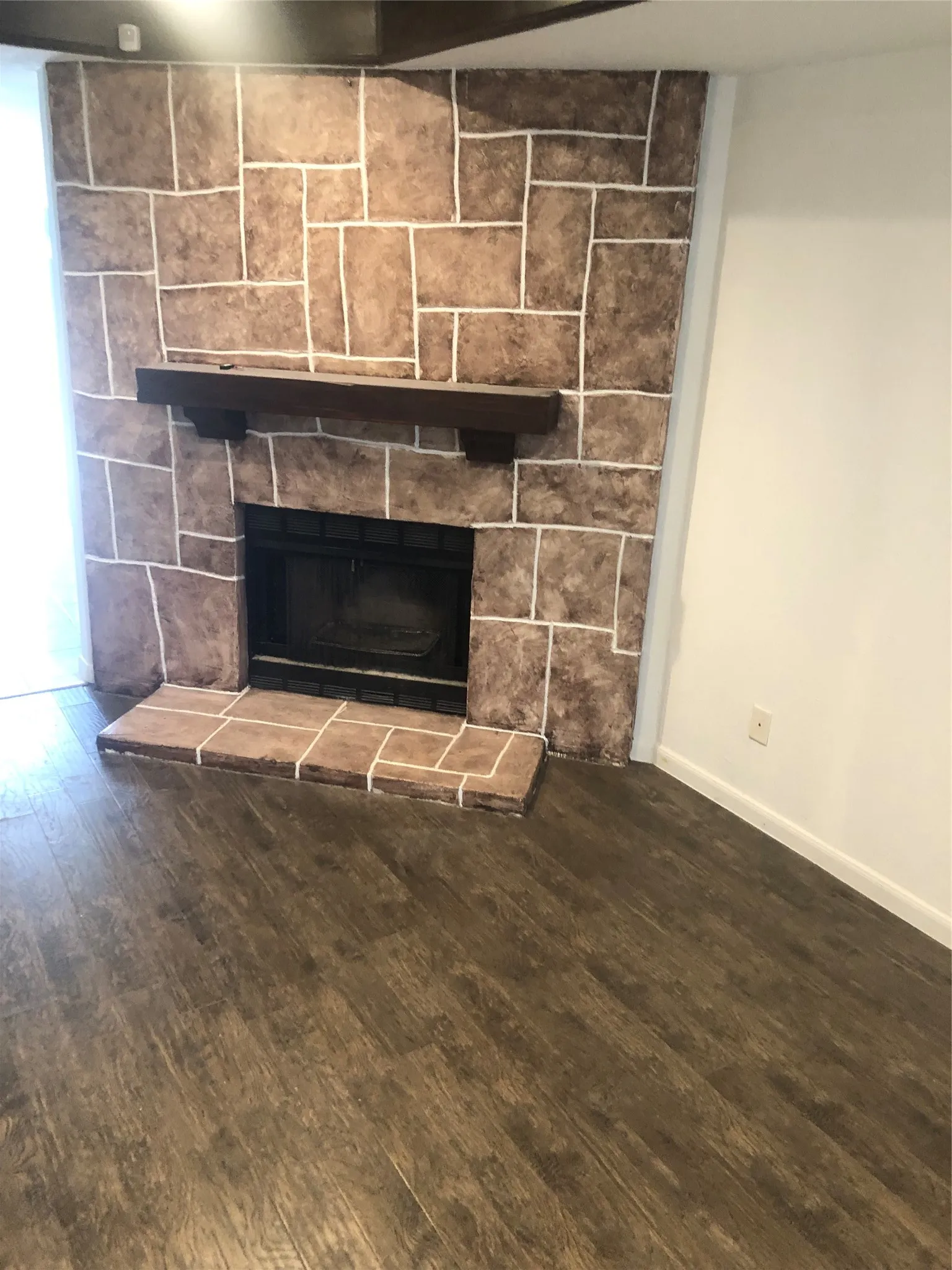 Stone-clad fireplace with a dark wood mantel and a tile hearth