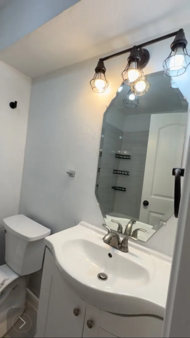 White vanity with integrated sink, brushed nickel faucet, and a decorative mirror