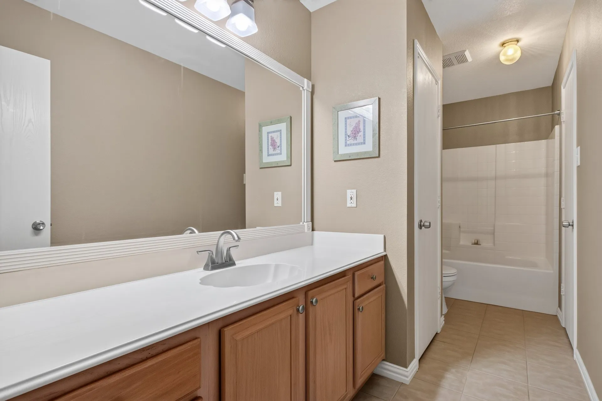 Extended vanity with ample counter space, integrated sink, and wood-finish cabinetry