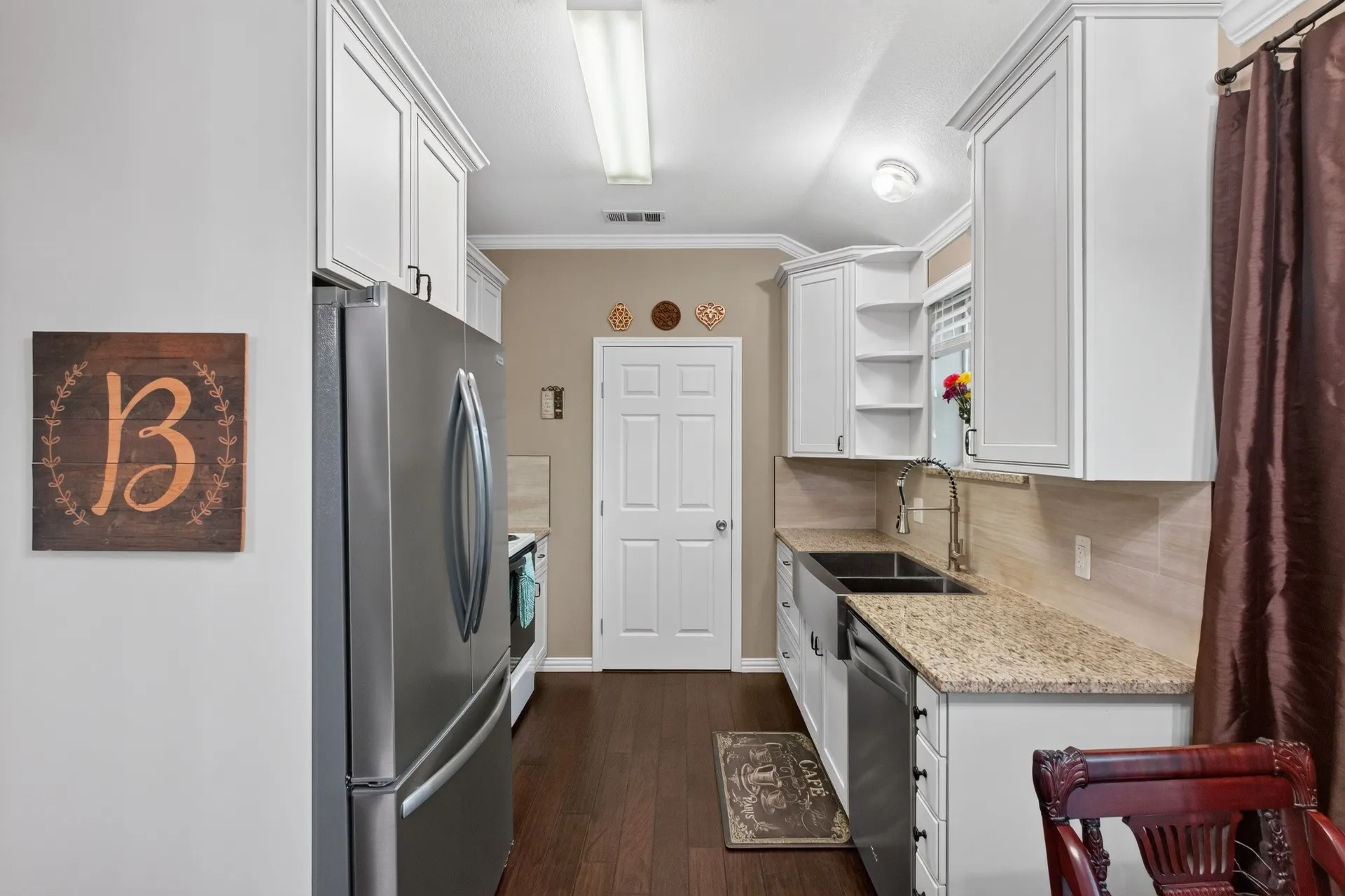 White cabinetry with crown molding, granite countertops, wood-finish flooring, and stainless steel appliances