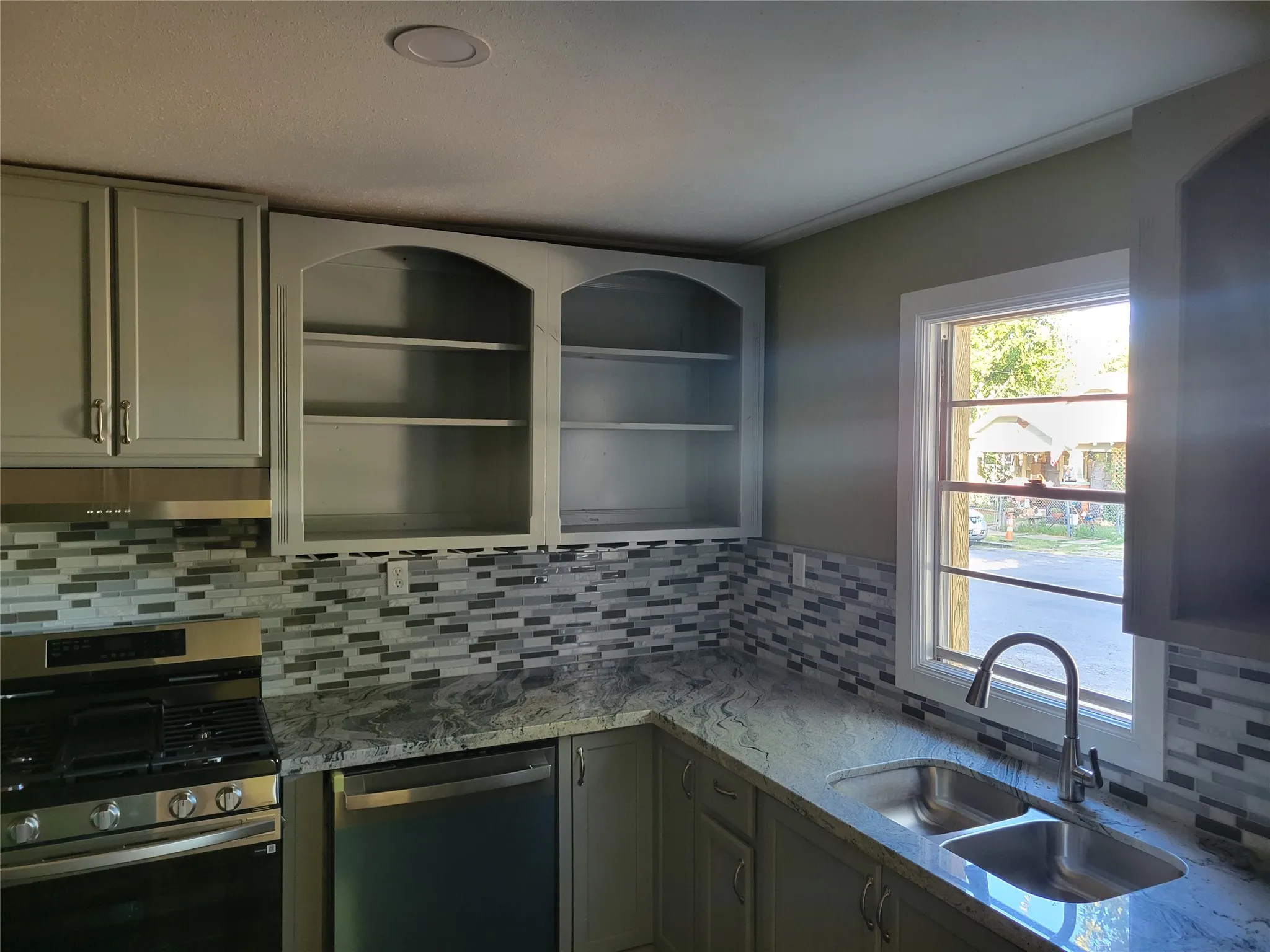 Kitchen featuring a dual-basin stainless steel sink, pull-down faucet, granite countertops, and a tiled backsplash
