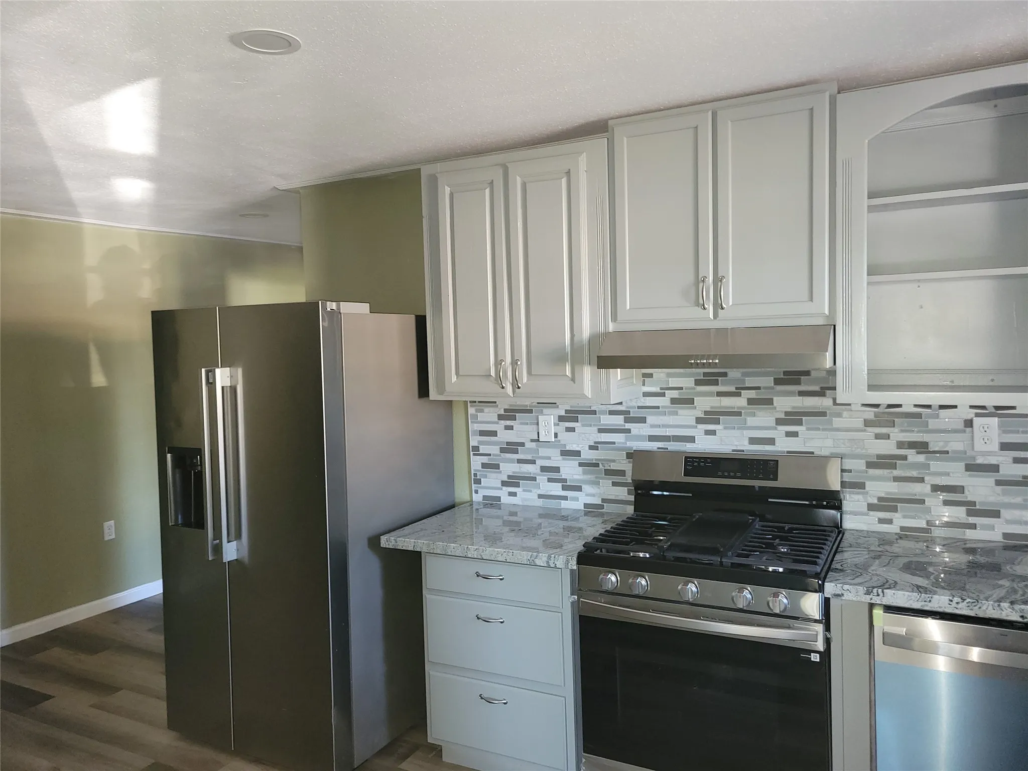 Stainless steel side-by-side refrigerator, gas range, and dishwasher
