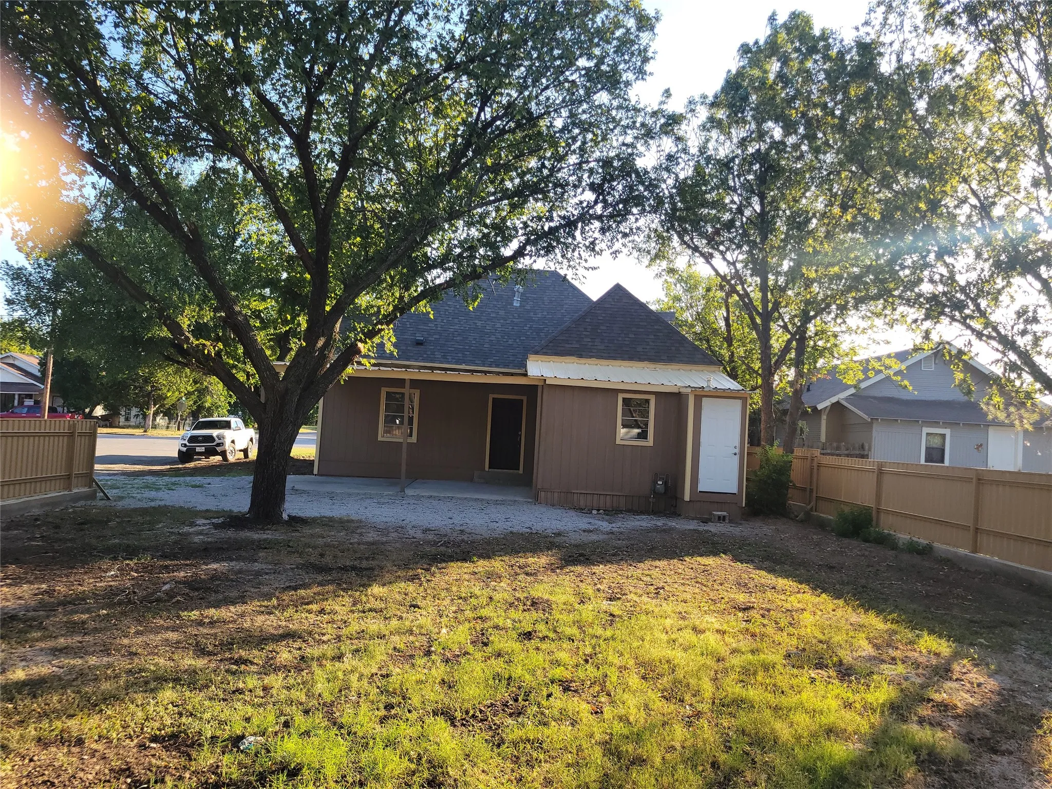 Rear elevation featuring brown siding, a covered patio, and a privacy fence