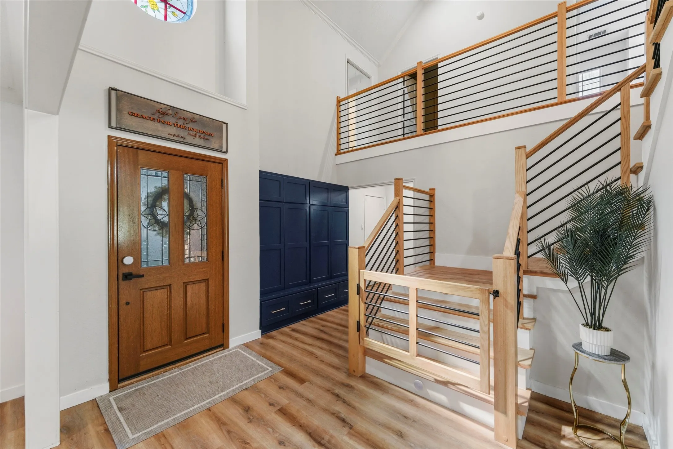 Entryway with wood-finish flooring, a wood-panel door with leaded glass inserts, and a high vaulted ceiling